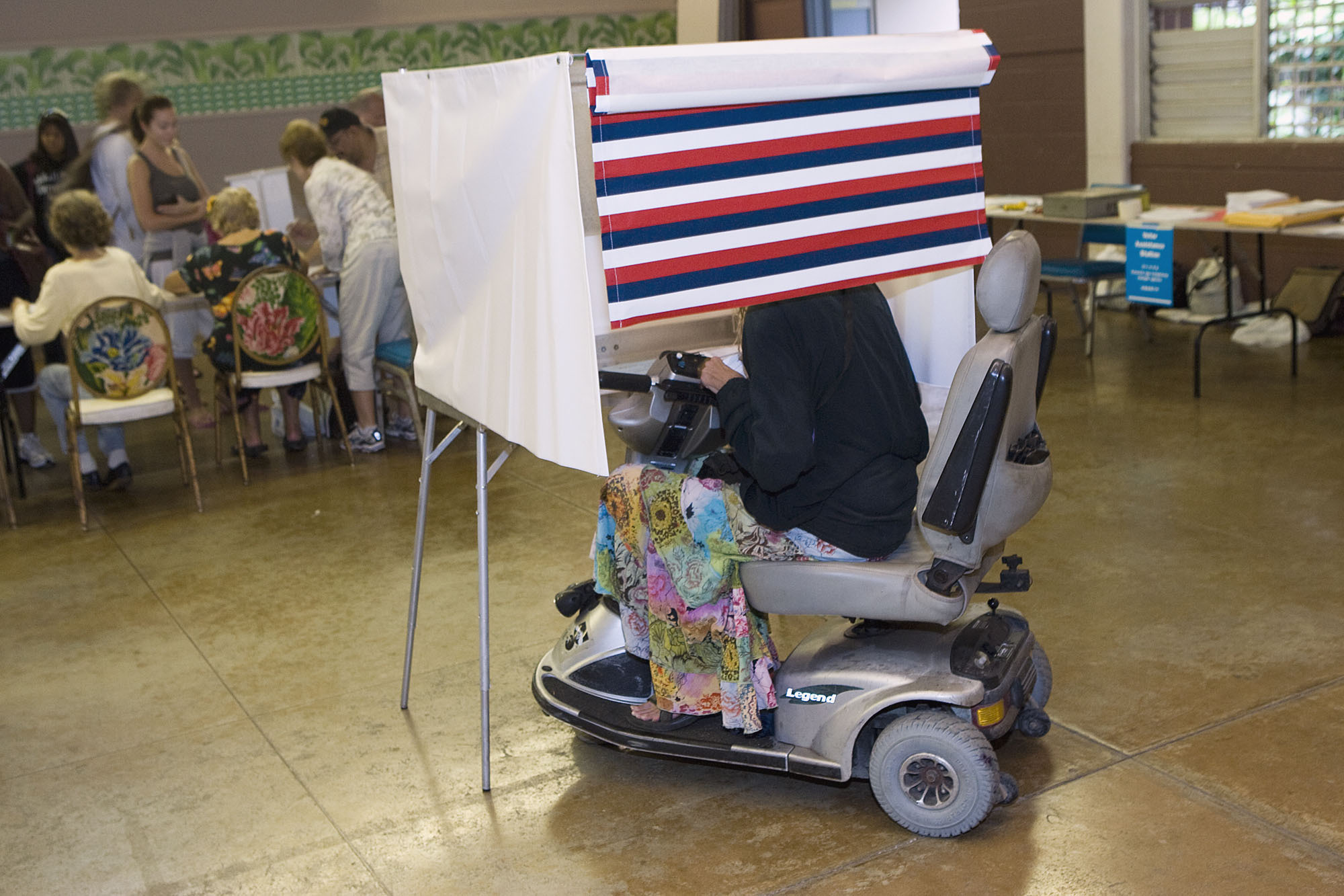 A woman in a motorized wheelchair casts her vote at the Waikiki Community Center in Honolulu, on Nov. 4, 2008. Voters and advocates say the hurdles that make people feel excluded from the electoral process aren't being addressed.  