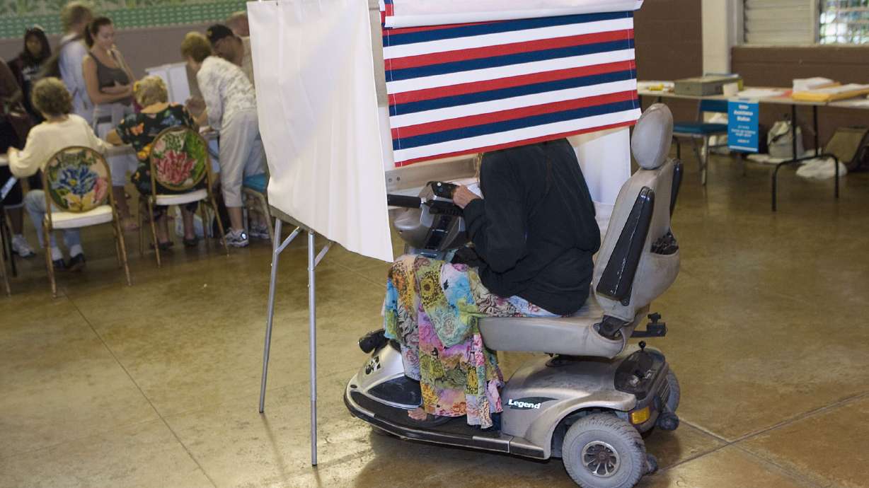 A woman in a motorized wheelchair casts her vote at the Waikiki Community Center in Honolulu, on Nov. 4, 2008. Voters and advocates say the hurdles that make people feel excluded from the electoral process aren't being addressed.