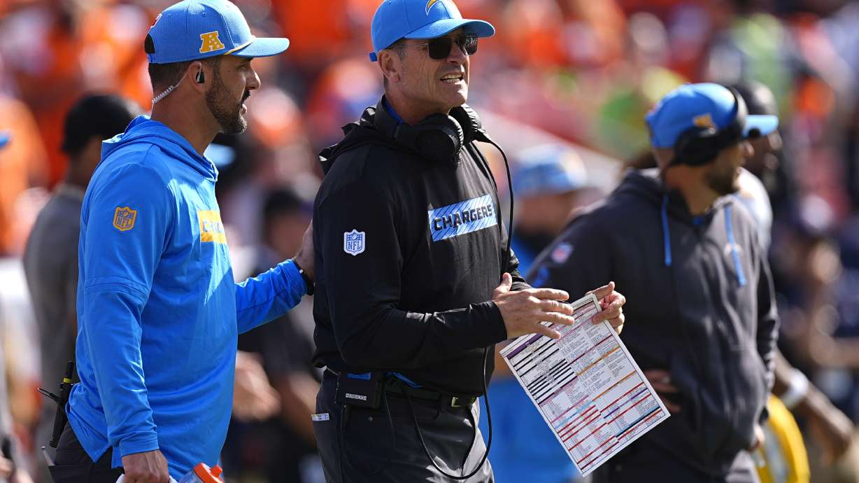 Los Angeles Chargers head coach Jim Harbaugh, center, stands on the sideline during the first half of an NFL football game against the Denver Broncos, Sunday, Oct. 13, 2024, in Denver.