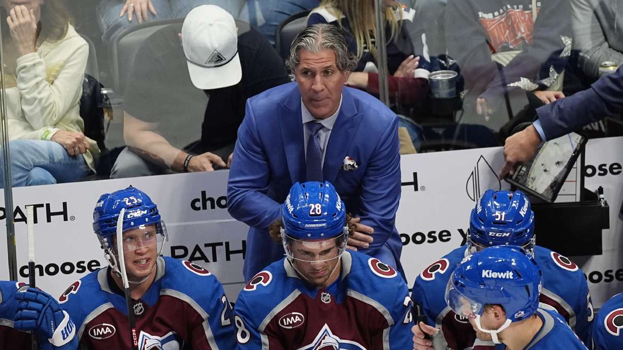 Colorado Avalanche head coach Jared Bednar, back, looks on from the team box in the third period of an NHL hockey game against the New York Islanders, Monday, Oct. 14, 2024, in Denver.