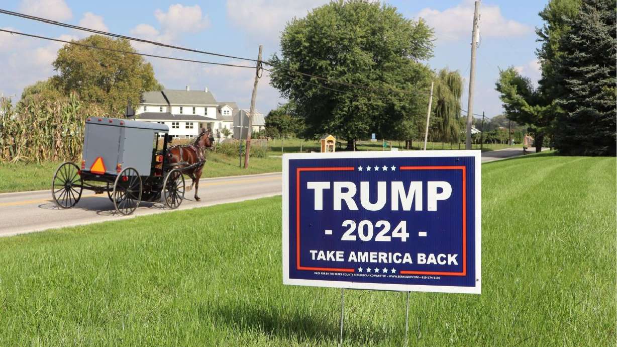 An Amish horse-drawn buggy passes a yard sign supporting former President Donald Trump in Ronks, Pa., on Oct. 3.