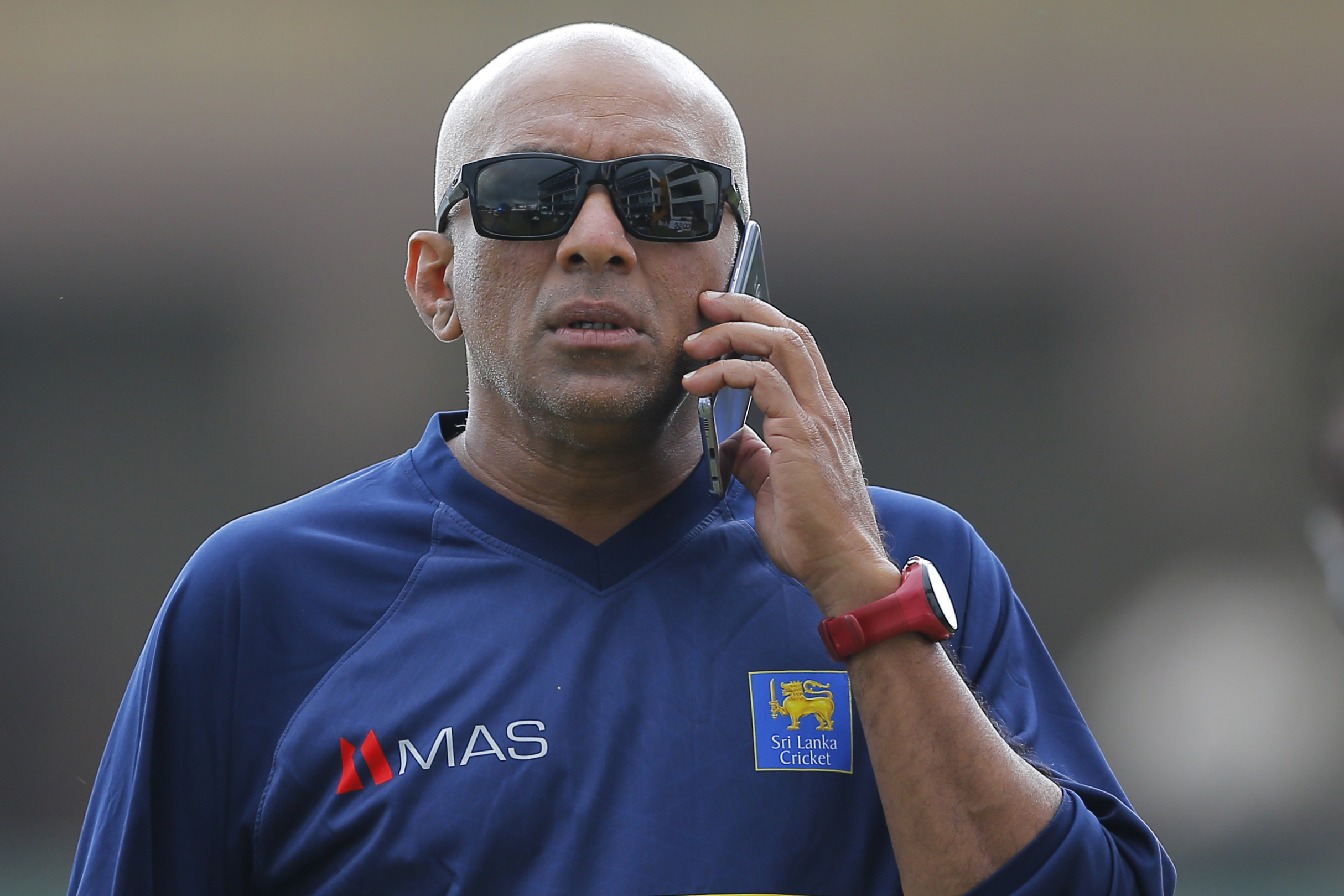 FILE - Sri Lanka's coach Chandika Hathurusinghe speaks from a mobile phone before a practice session ahead of the first test cricket match against South Africa in Galle, Sri Lanka, Wednesday, July 11, 2018.