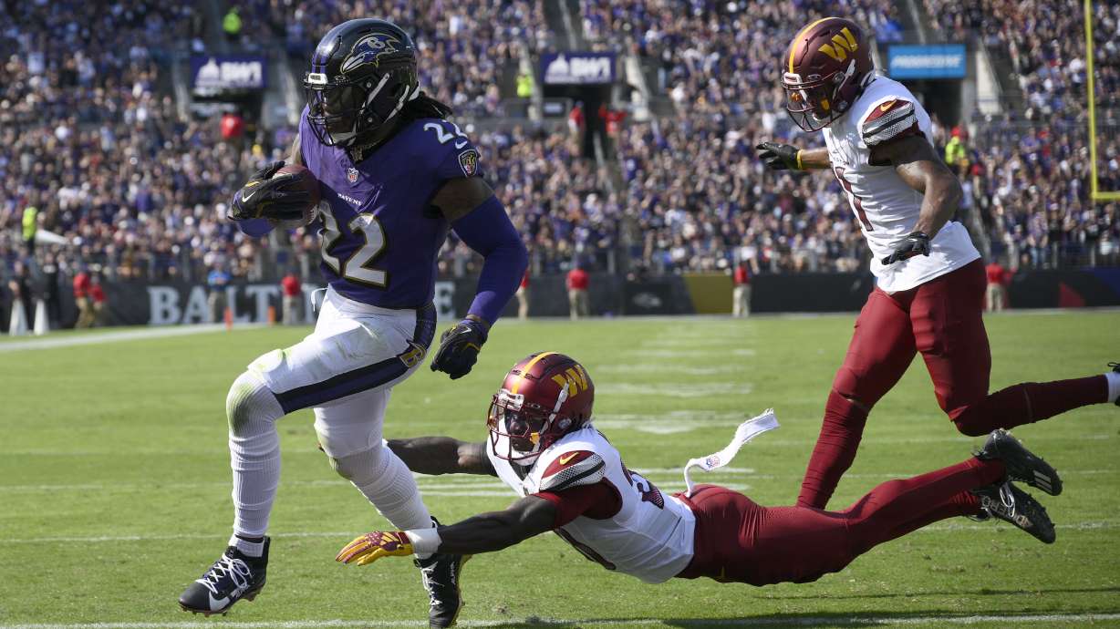 Baltimore Ravens running back Derrick Henry (22) scores past Washington Commanders safety Quan Martin and safety Jeremy Chinn, right, during the first half of an NFL football game Sunday, Oct. 13, 2024, in Baltimore.