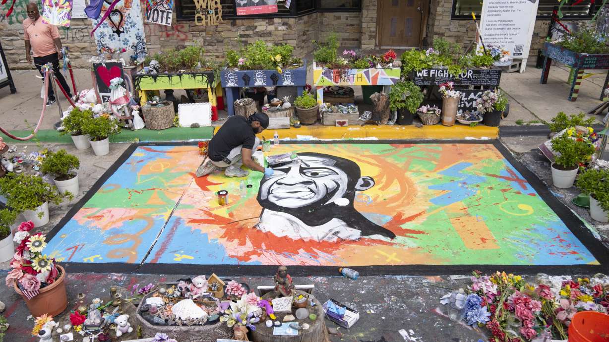 Antonio Jenkins paints a mural of George Floyd on May 25 at the site where he was murdered by a police officer in 2020 in Minneapolis. A Minnesota school district banned a police officer from working as a substitute teacher regarding actions that included using a student to reenact Floyd's death.