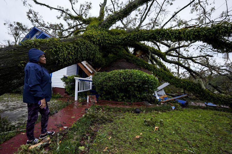 Rhonda Bell looks on after an Oak tree landed on her 100-year-old home after Hurricane Helene moved through, Sept. 27, in Valdosta, Ga.