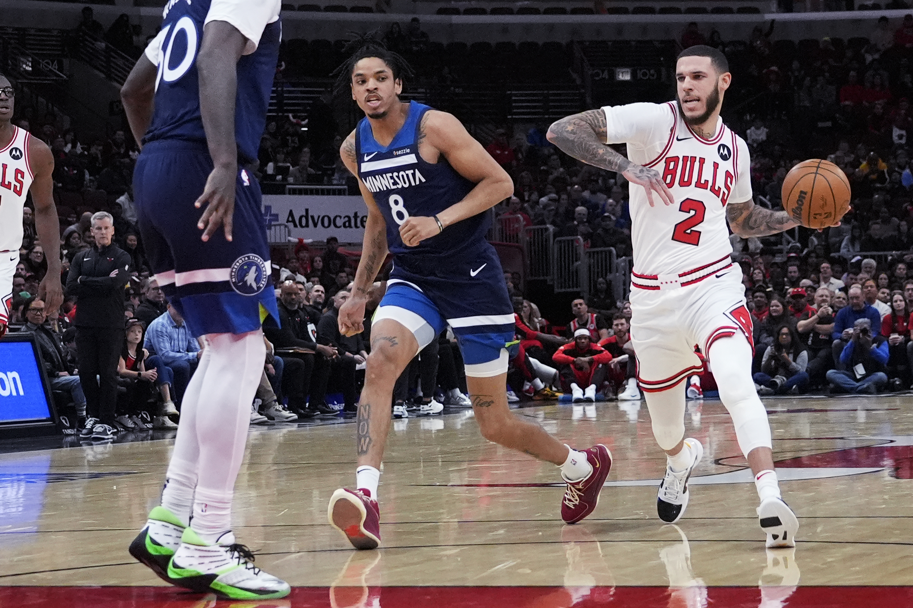Chicago Bulls guard Lonzo Ball (2) drives as he looks to pass against Minnesota Timberwolves forward Josh Minott (8) and forward Julius Randle during the first half of an NBA preseason basketball game in Chicago, Wednesday, Oct. 16, 2024. 