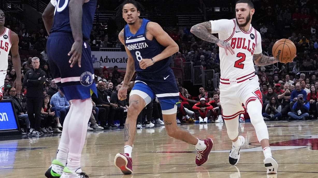 Chicago Bulls guard Lonzo Ball (2) drives as he looks to pass against Minnesota Timberwolves forward Josh Minott (8) and forward Julius Randle during the first half of an NBA preseason basketball game in Chicago, Wednesday, Oct. 16, 2024.