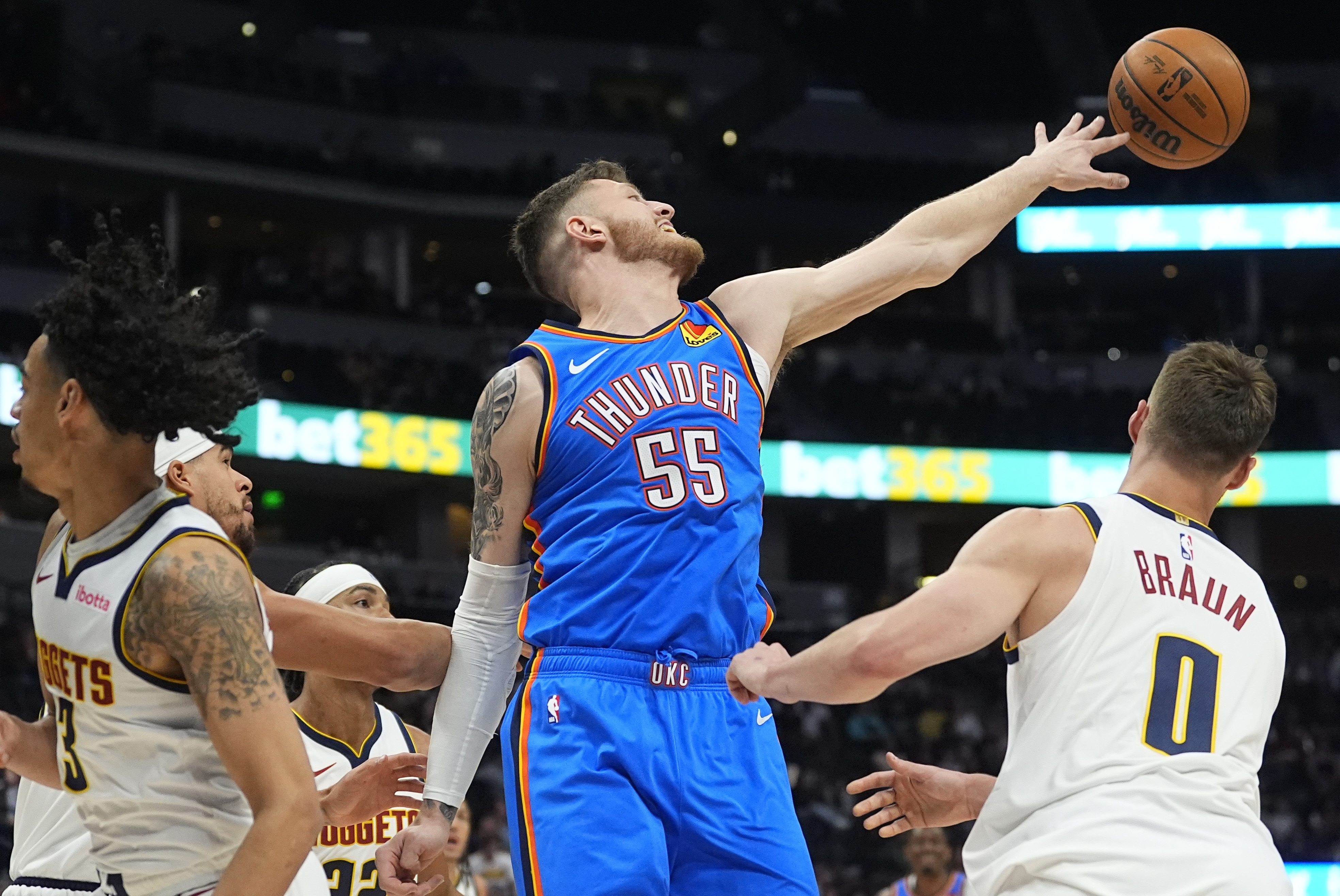 Oklahoma City Thunder center Isaiah Hartenstein, center, reaches out for a rebound as Denver Nuggets guards Trey Alexander, left, and Christian Braun defend in the first half of an NBA preseason basketball game Tuesday, Oct. 15, 2024, in Denver. 