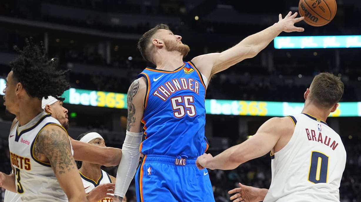 Oklahoma City Thunder center Isaiah Hartenstein, center, reaches out for a rebound as Denver Nuggets guards Trey Alexander, left, and Christian Braun defend in the first half of an NBA preseason basketball game Tuesday, Oct. 15, 2024, in Denver.