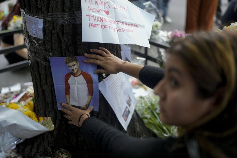 A fan of former One Direction singer Liam places a photo of him on a tree outside the hotel where he was found dead after falling from a balcony the previous day in Buenos Aires, Argentina, Thursday.