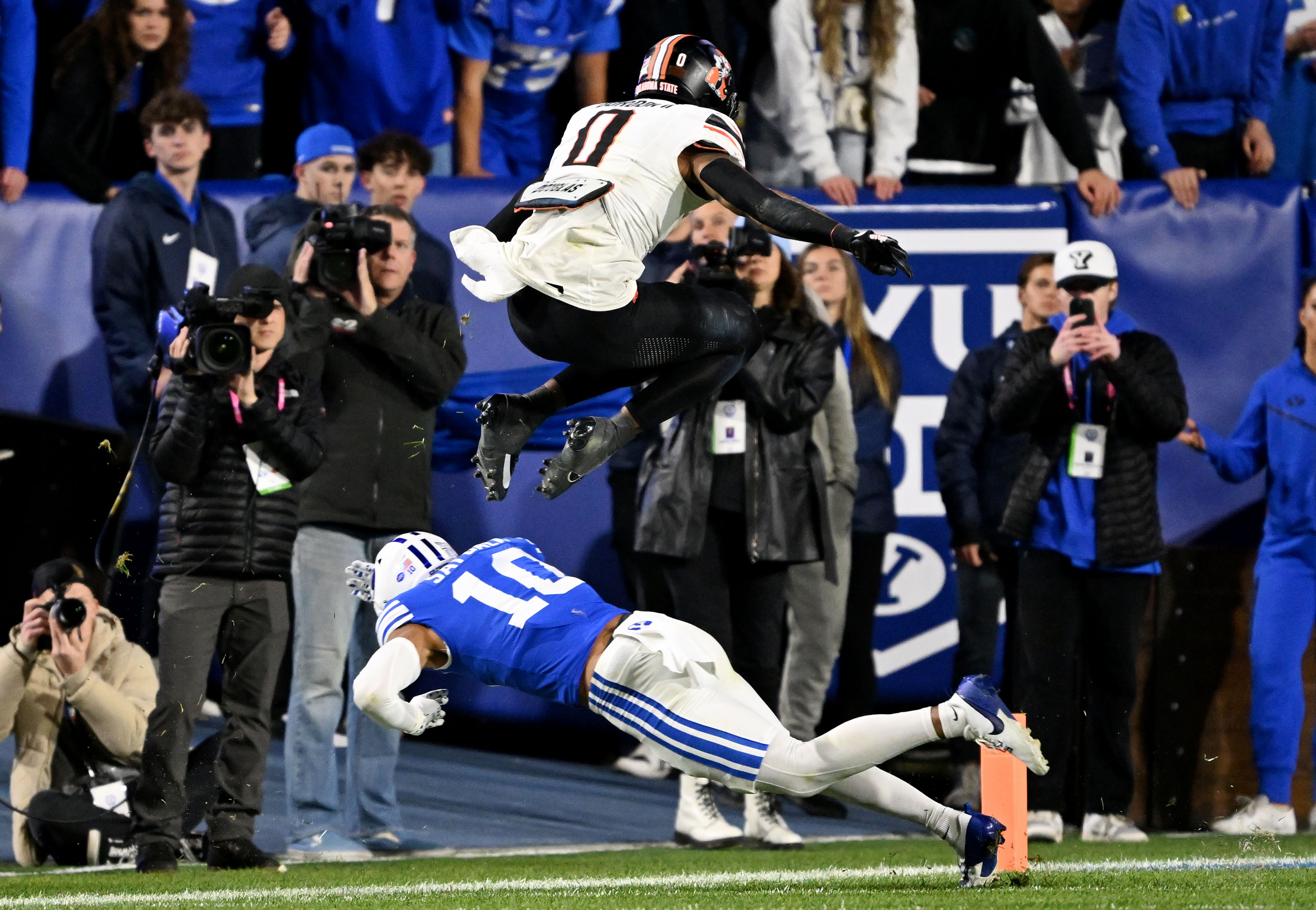 Oklahoma State running back Ollie Gordon II (0) jumps over BYU safety Faletau Satuala (10) as BYU and Oklahoma State play at LaVell Edwards Stadium in Provo on Friday, Oct. 18, 2024.