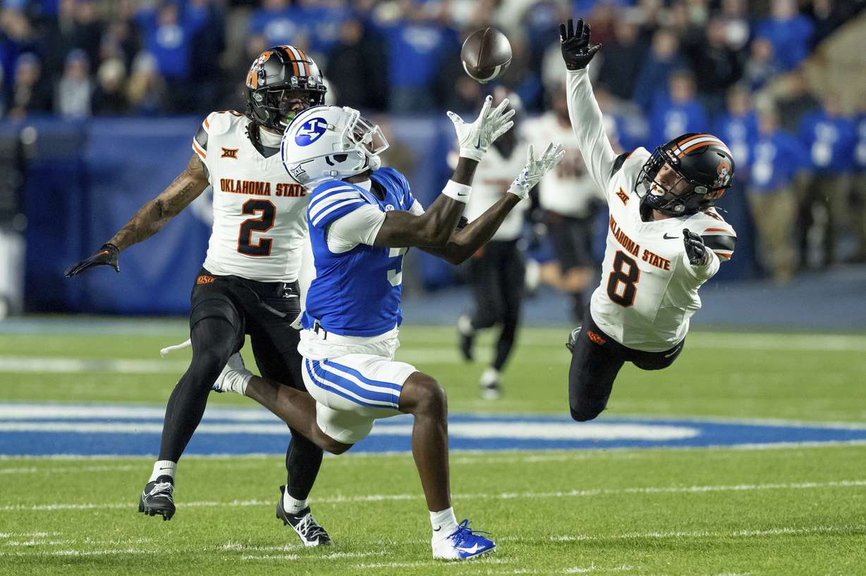 BYU wide receiver Darius Lassiter makes a catch ahead of Oklahoma State cornerback Korie Black (2) and safety Parker Robertson (8) in the first half of an NCAA college football game, Friday, Oct. 18, 2024, in Provo, Utah.