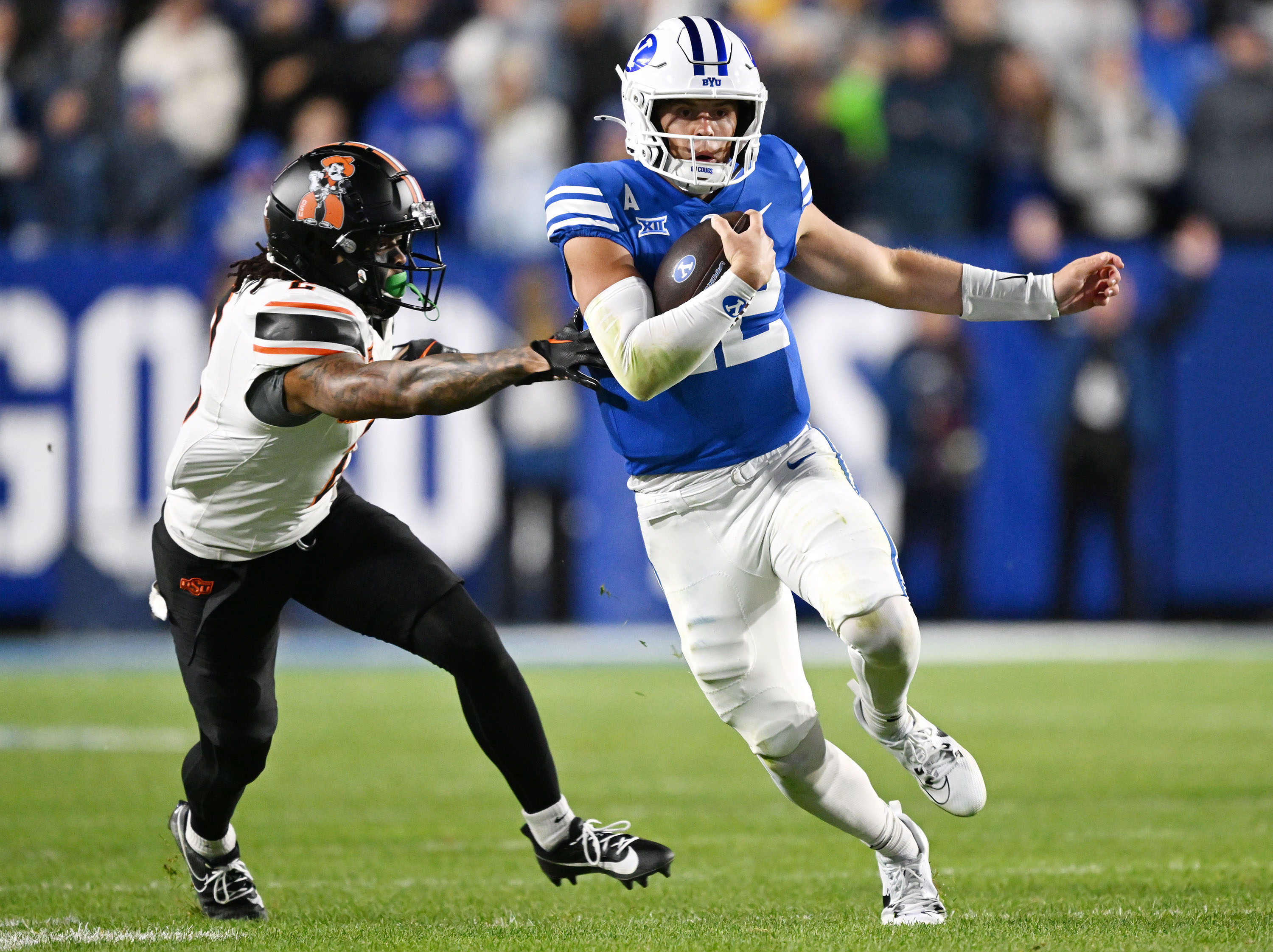 Brigham Young quarterback Jake Retzlaff (12) runs just ahead of Oklahoma State cornerback Korie Black (2) as he gets away for a big gain late in the fourth quarter as BYU and Oklahoma State play in Provo at LaVell Edwards Stadium on Friday Oct. 18, 2024. BYU won 38-35.