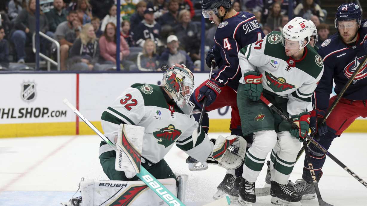 Minnesota Wild goalie Filip Gustavsson (32) makes a stop in front of Columbus Blue Jackets forward Cole Sillinger (4), forward Mathieu Olivier (24) and Wild defenseman Declan Chisholm (47) during the second period of an NHL hockey game in Columbus, Ohio, Saturday, Oct. 19, 2024.