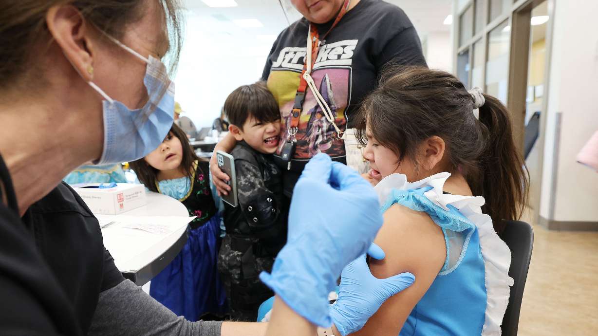 Sara Avalos watches her daughter Kiara Avalos, 7, get her COVID-19 vaccine at the Community Health Center Neighborhood Clinic in Salt Lake City on Oct. 28, 2022.