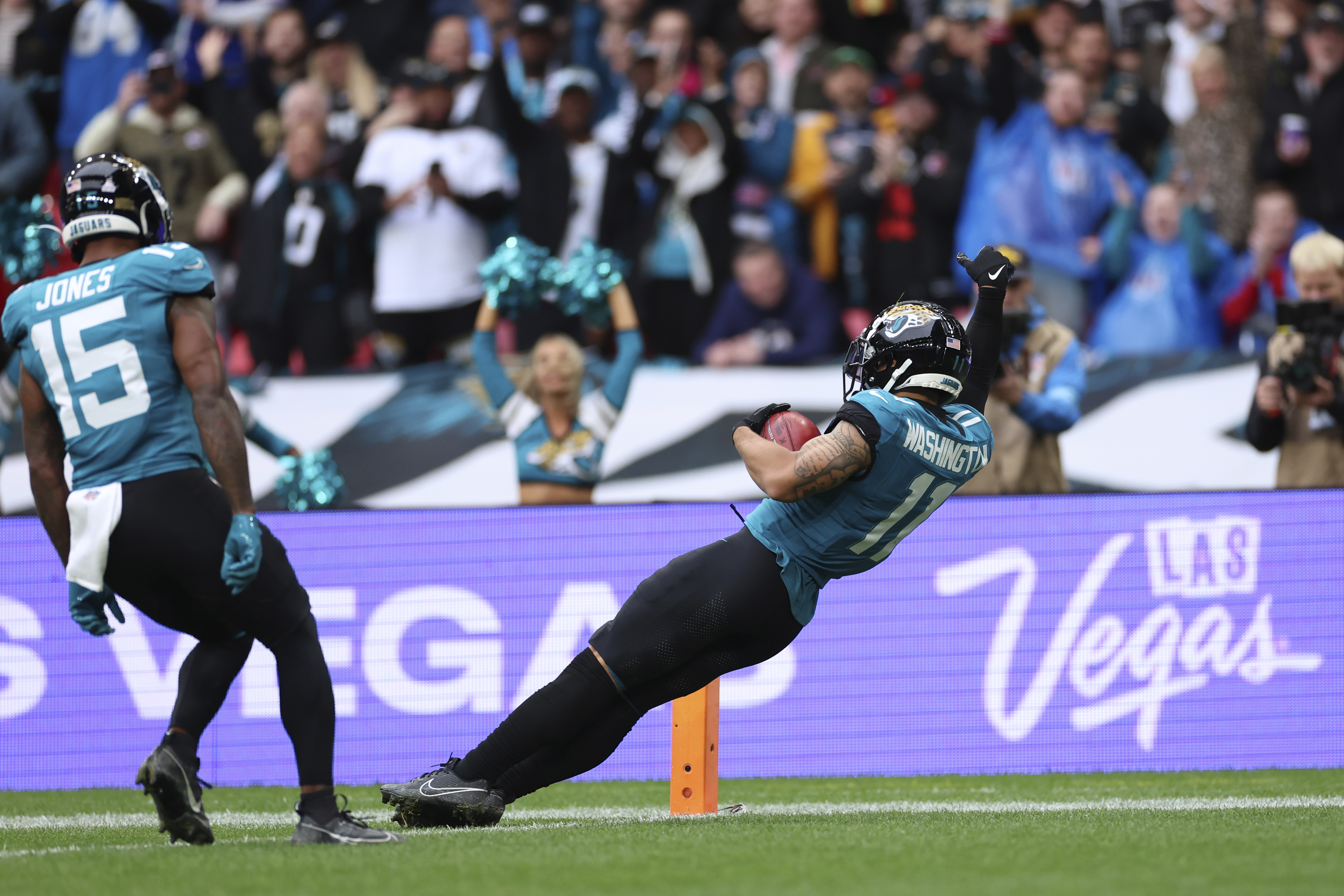 Teammates cheer as Jacksonville Jaguars' Parker Washington (11) falls into the endzone for a 96-yard touchdown on a punt return during the first half of an NFL football game against the New England Patriots, Sunday, Oct. 20, 2024, in London. 