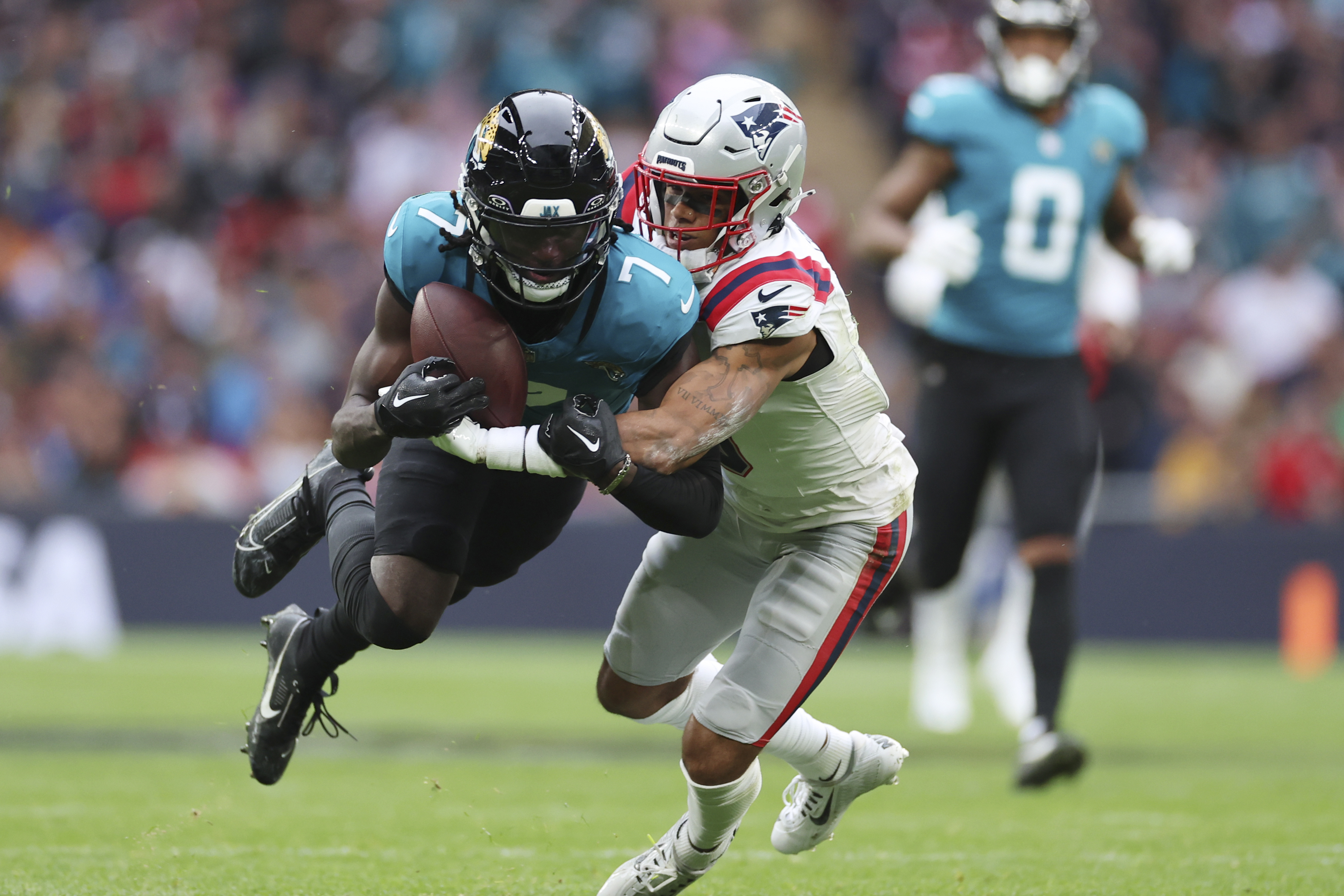 Jacksonville Jaguars wide receiver Brian Thomas Jr. (7) is tackled by New England Patriots cornerback Christian Gonzalez (0) during the first half of an NFL football game, Sunday, Oct. 20, 2024, in London. 
