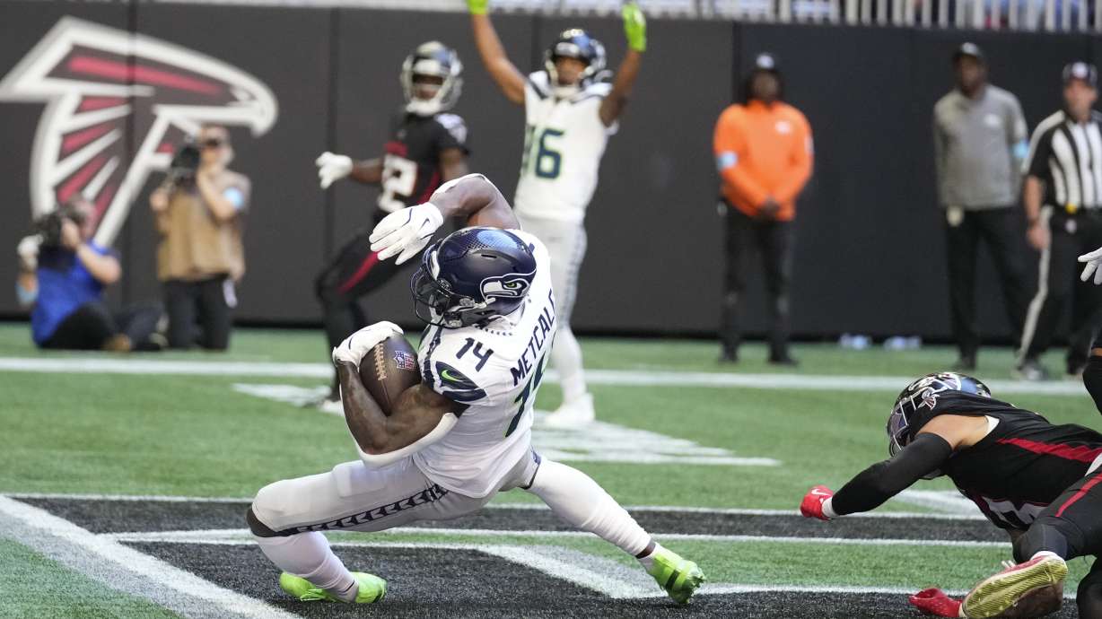 Seattle Seahawks wide receiver DK Metcalf (14) scors a touchdown as Atlanta Falcons safety Jessie Bates III (3) defends during the first half of an NFL football game, Sunday, Oct. 20, 2024, in Atlanta.
