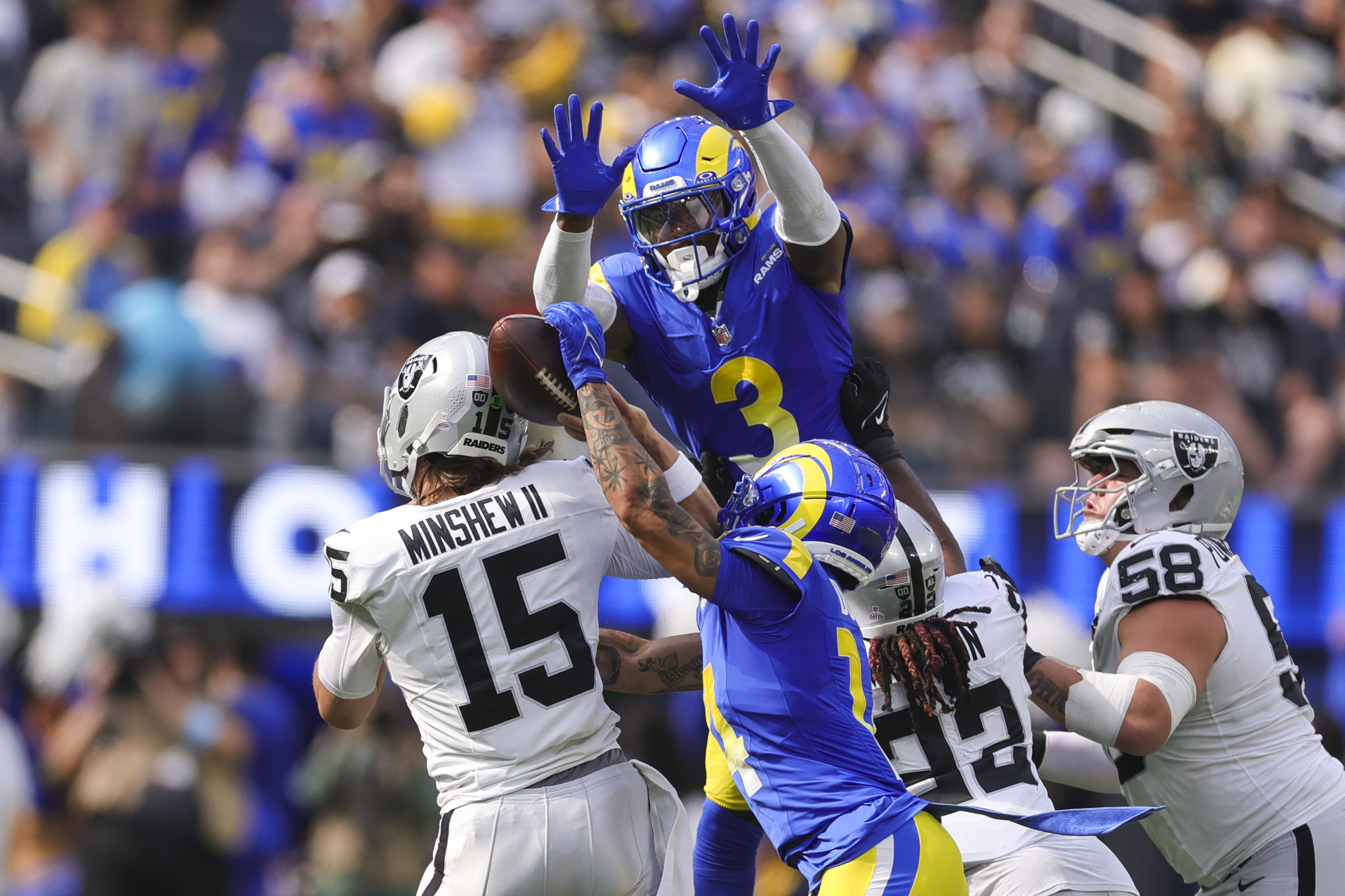 Los Angeles Rams cornerback Cobie Durant (14) forces a fumble against Las Vegas Raiders quarterback Gardner Minshew (15) as Rams safety Kamren Curl (3) jumps to defend during the first half of an NFL football game Sunday, Oct. 20, 2024, in Inglewood, Calif. 