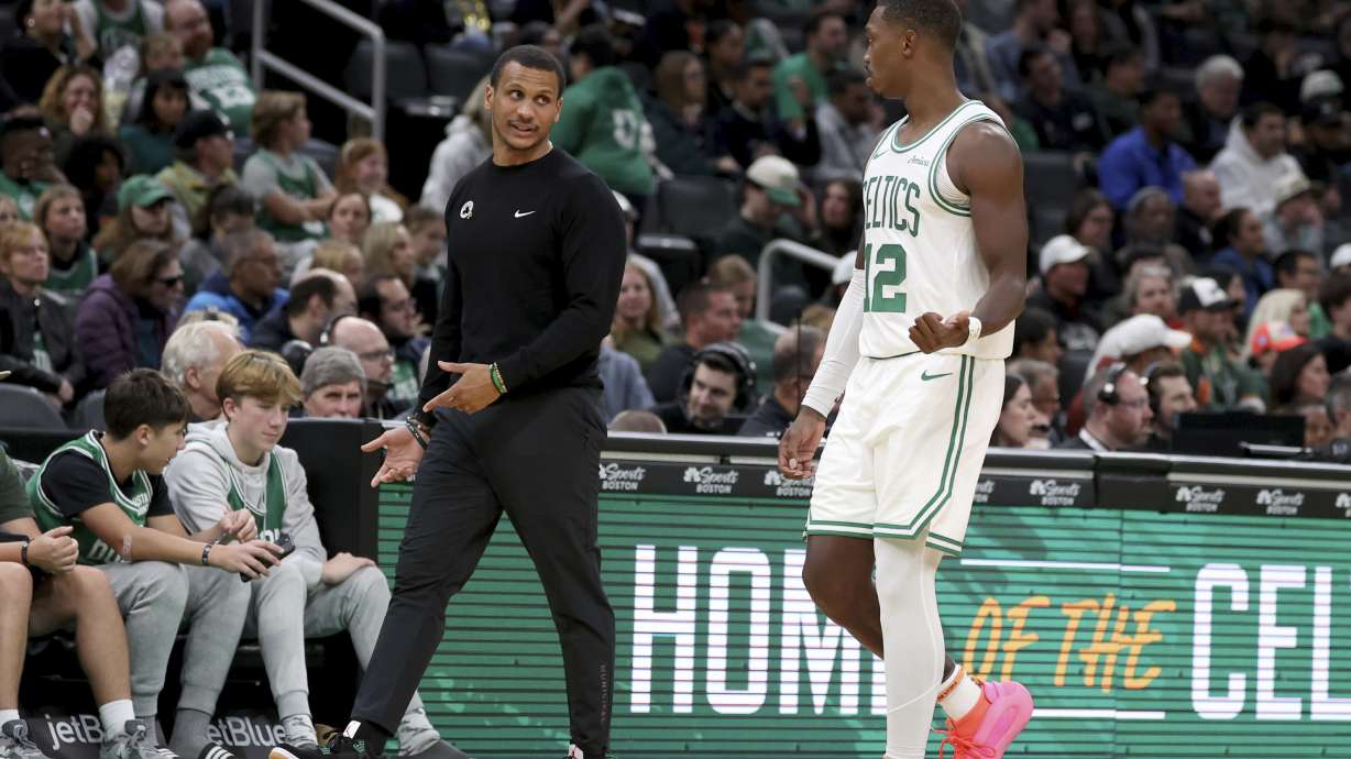 Boston Celtics head coach Joe Mazzulla, front left, speaks with Boston Celtics guard Lonnie Walker IV (12) who walks to the team bench during the second half of a preseason NBA basketball game against the Toronto Raptors, Sunday, Oct. 13, 2024, in Boston.