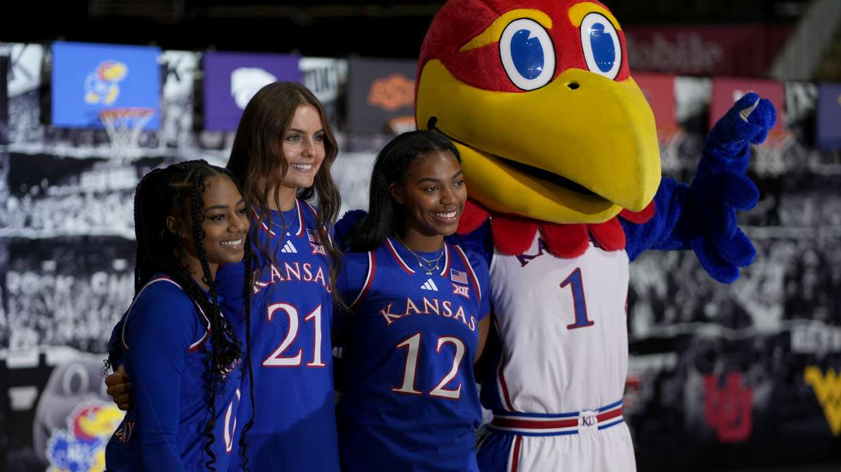 Kansas' Wyvette Mayberry, left, Elle Evans (21) and S'Mya Nichols (12) pose with the Kansas mascot during the NCAA college Big 12 women's basketball media day, Tuesday, Oct. 22, 2024, in Kansas City, Mo.