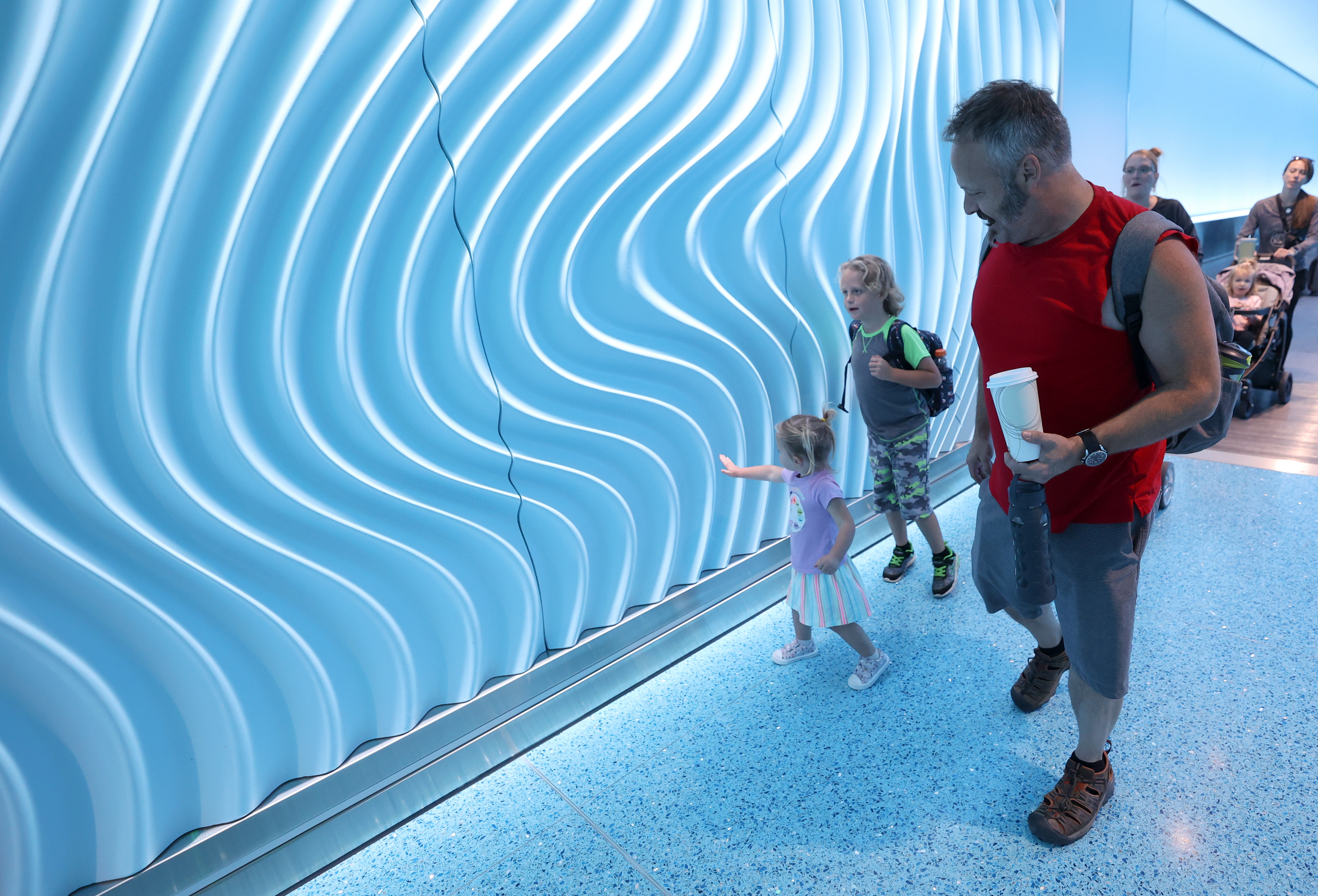 Millie Geving, Tripp Geving and Billy Geving walk through the River Tunnel, which connects Concourse A and Concourse B at the Salt Lake City International Airport in Salt Lake City on Tuesday.