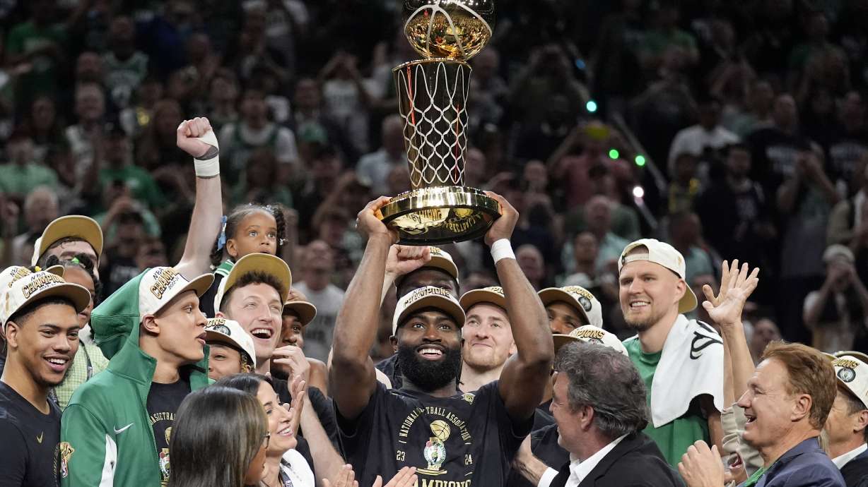 FILE - Boston Celtics guard Jaylen Brown, center, holds up the Larry O'Brien Championship Trophy as he celebrates with the team after they won the NBA basketball championship with a Game 5 victory over the Dallas Mavericks, Monday, June 17, 2024, in Boston.