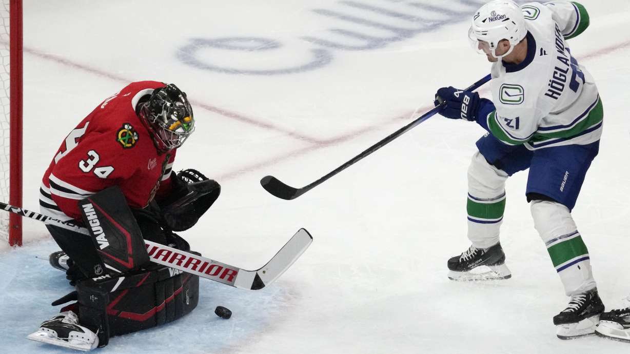 Chicago Blackhawks goaltender Petr Mrazek, left, saves a shot by Vancouver Canucks left wing Nils Hoglander during the second period of an NHL hockey game in Chicago, Tuesday, Oct. 22, 2024.