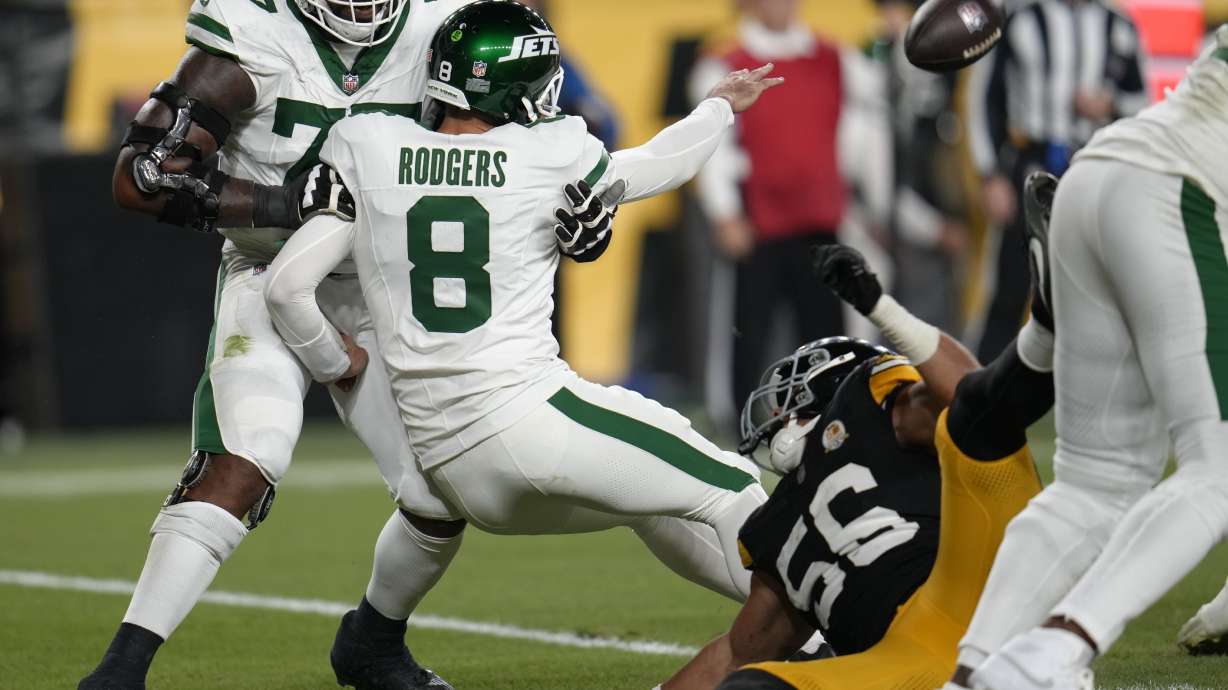New York Jets quarterback Aaron Rodgers (8) tosses the ball as he is brought down by Pittsburgh Steelers linebacker Alex Highsmith (56) in the first half of an NFL football game in Pittsburgh, Sunday, Oct. 20, 2024.
