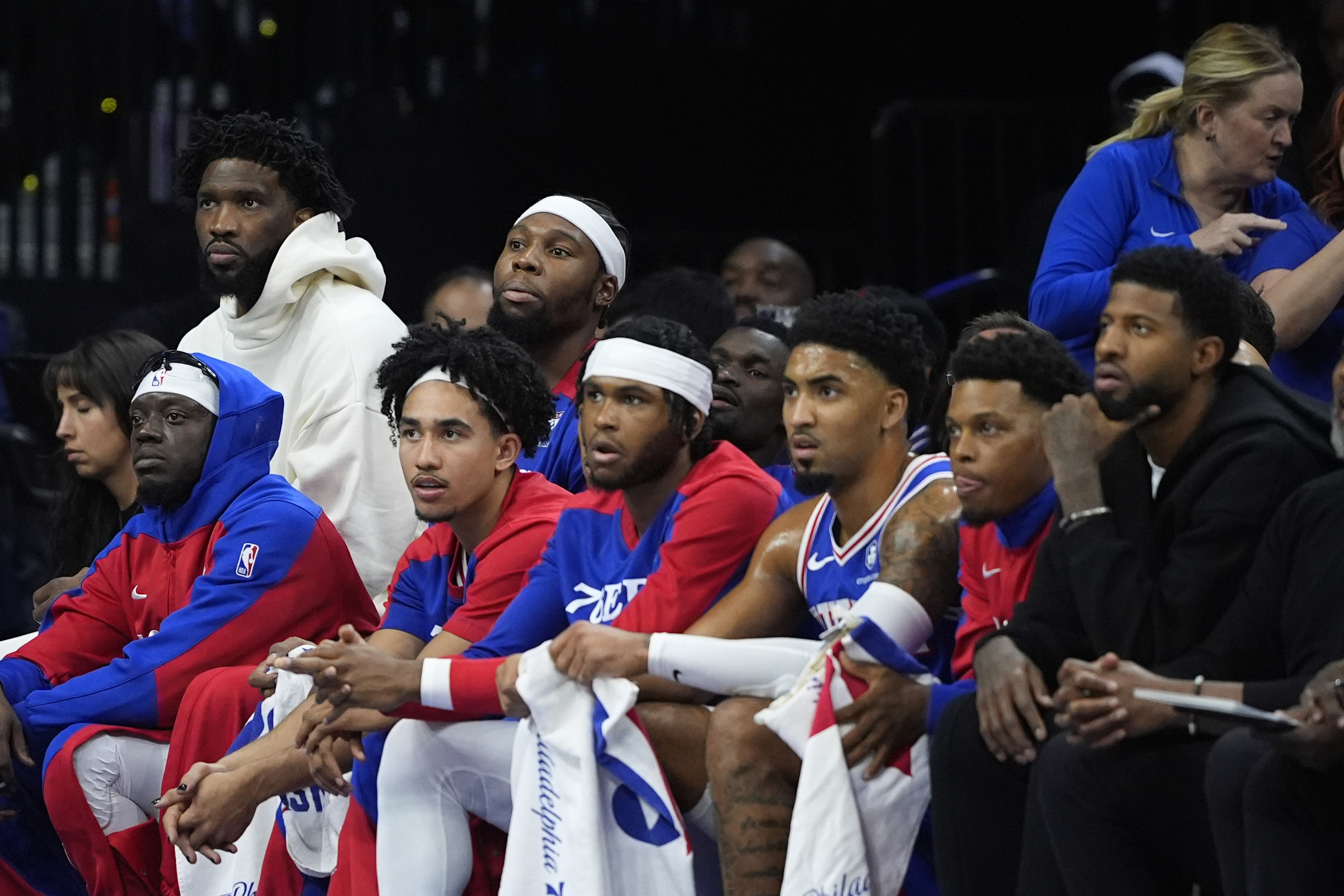Philadelphia 76ers' Joel Embiid, top left, and Paul George, bottom right, watch from the bench during the first half of an NBA basketball game against the Milwaukee Bucks, Wednesday, Oct. 23, 2024, in Philadelphia.