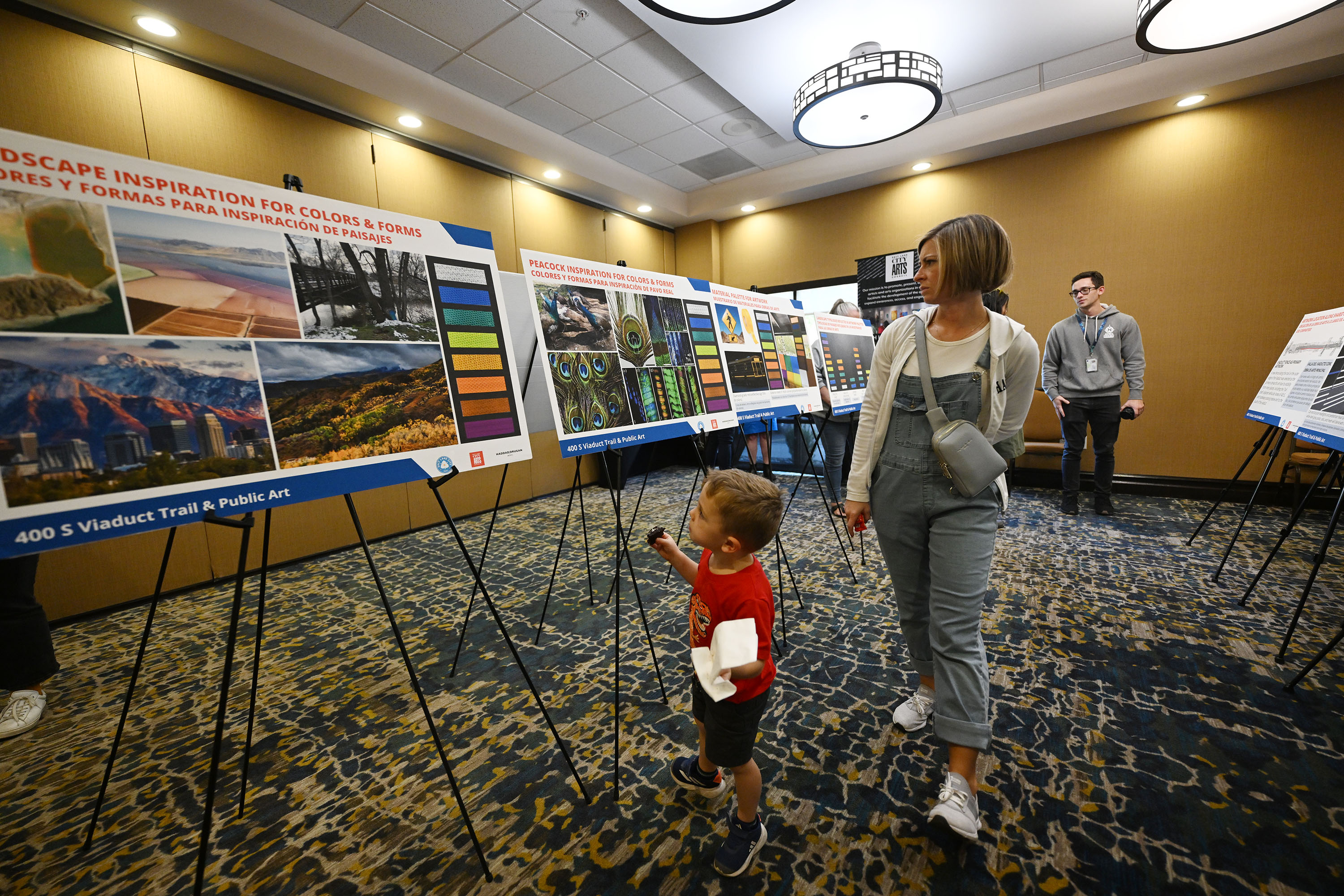 Carrie Colton walks with her son Peter Colton as they look at the different displays by Salt Lake City’s Transportation Division and the Salt Lake City Arts Council for members of the community to explore plans for a new multiuse trail on 400 South, from 900 West to 200 West, at the Hampton Inn in Salt Lake City on Wednesday. The boards show the color palette for the proposed bridge artwork.