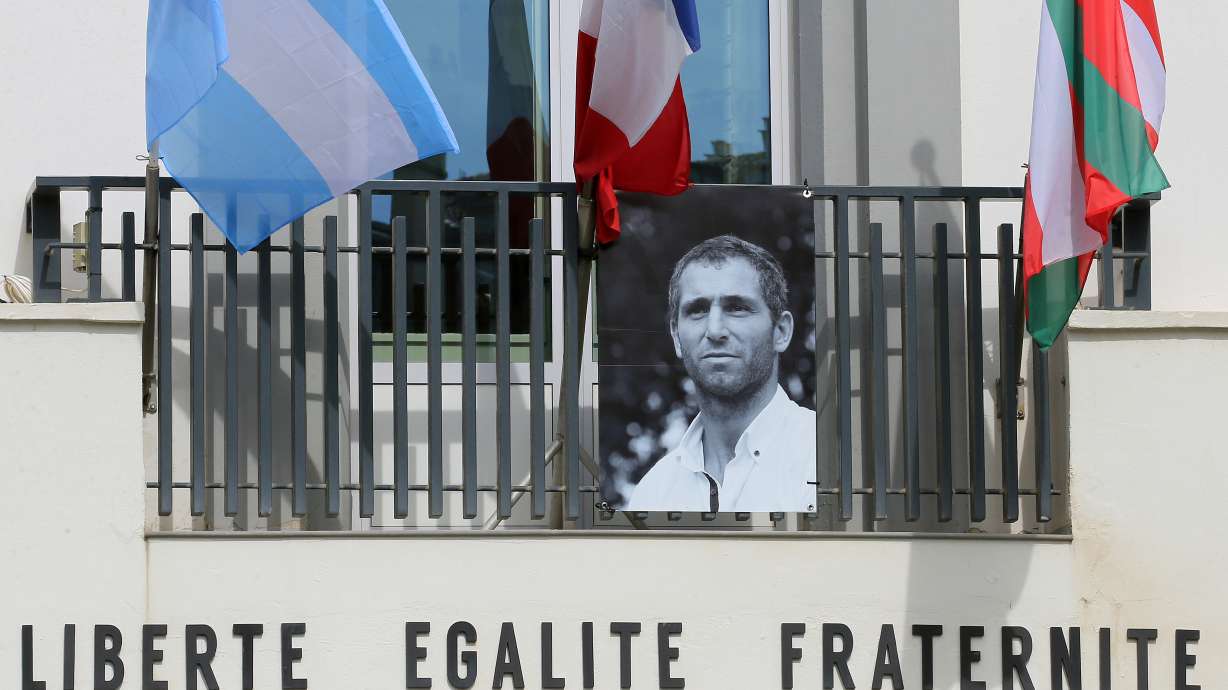 FILE - A portrait of Federico Martin Aramburu is seen under Argentinian, French and Basque flags hanging on the balcony of the town hall in Biarritz, France, March 25, 2022.