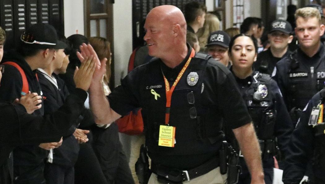 Officer Colten Johansen high-fives Ogden High students after he assisted in the law enforcement response to a call alleging an active shooter was inside the school. He and other officers were publicly lauded for their quick response on March 29, 2023. Johansen was arrested Thursday.