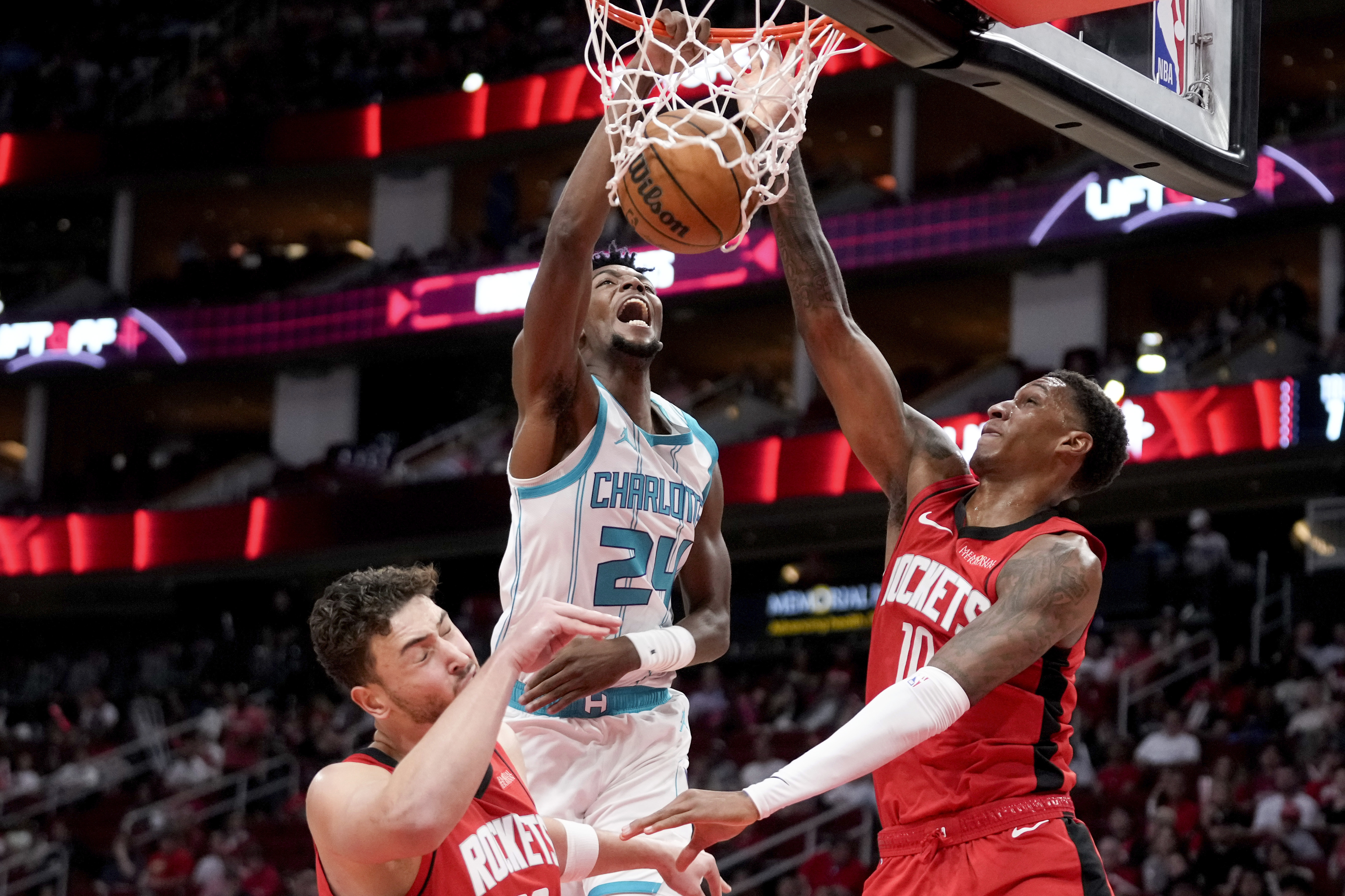 Charlotte Hornets forward Brandon Miller (24) dunks as Houston Rockets center Alperen Sengun, left, and forward Jabari Smith Jr. defend during the first half of an NBA basketball game Wednesday, Oct. 23, 2024, in Houston.