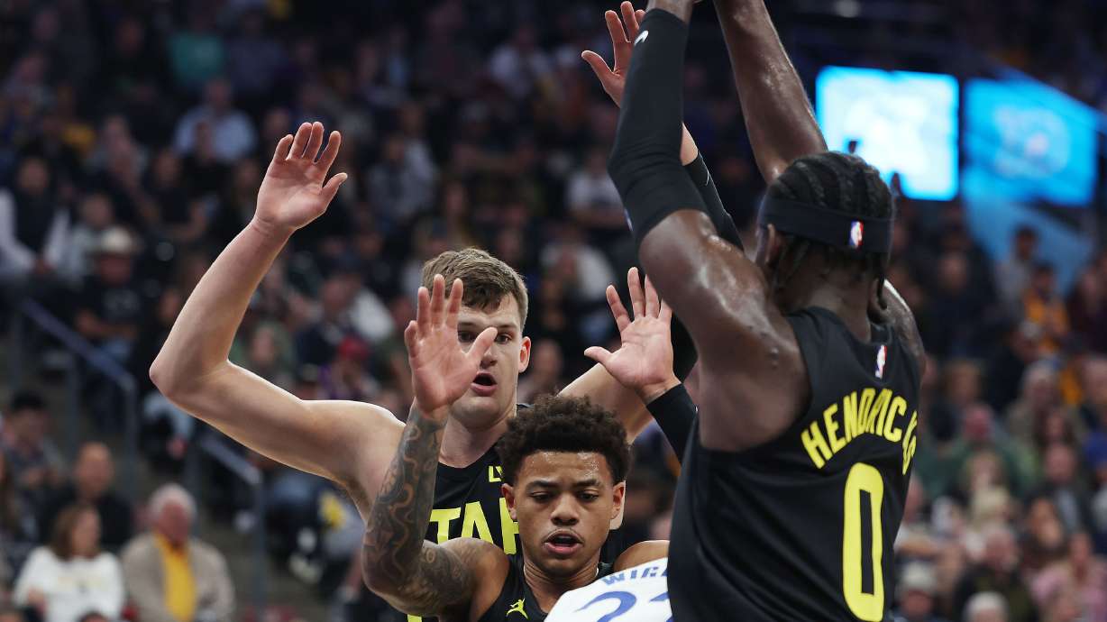 Several Jazz players defend Golden State Warriors forward Andrew Wiggins (22) in Salt Lake City on Friday, Oct. 25, 2024.
