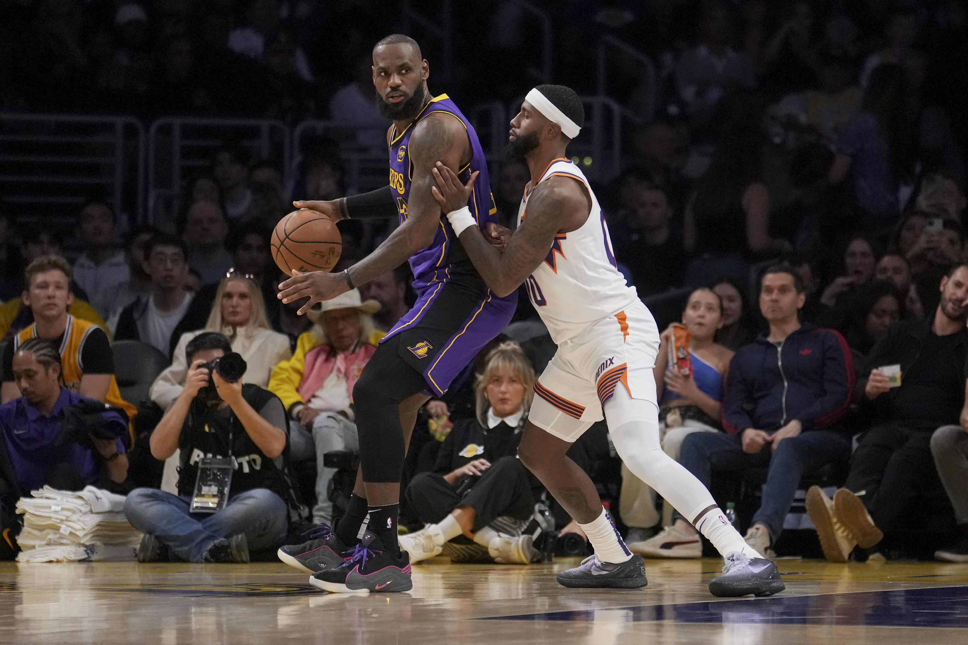 Los Angeles Lakers forward LeBron James, left, dribbles against Phoenix Suns forward Royce O'Neale, right, during the first half of an NBA basketball game against the in Los Angeles, Friday, Oct. 25, 2024. 