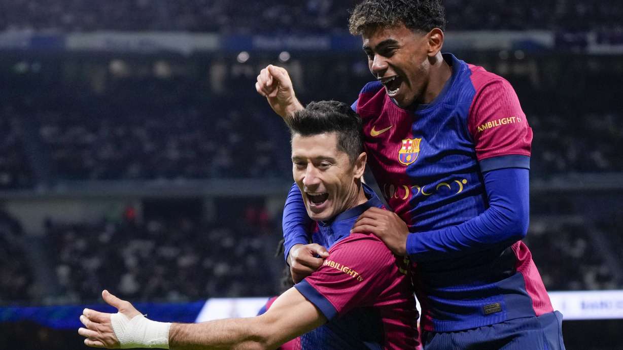 Barcelona's Robert Lewandowski celebrates after scoring his side's second goal with Lamine Yamal, right, during a Spanish La Liga soccer match between Real Madrid and Barcelona at the Santiago Bernabeu stadium in Madrid, Spain, Saturday, Oct. 26, 2024.