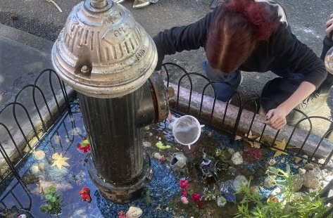 A woman tends to the makeshift aquarium goldfish pool created by a leaky fire hydrant in the Brooklyn borough of New York, Sept. 8. The guerrilla aquarium has been removed.
