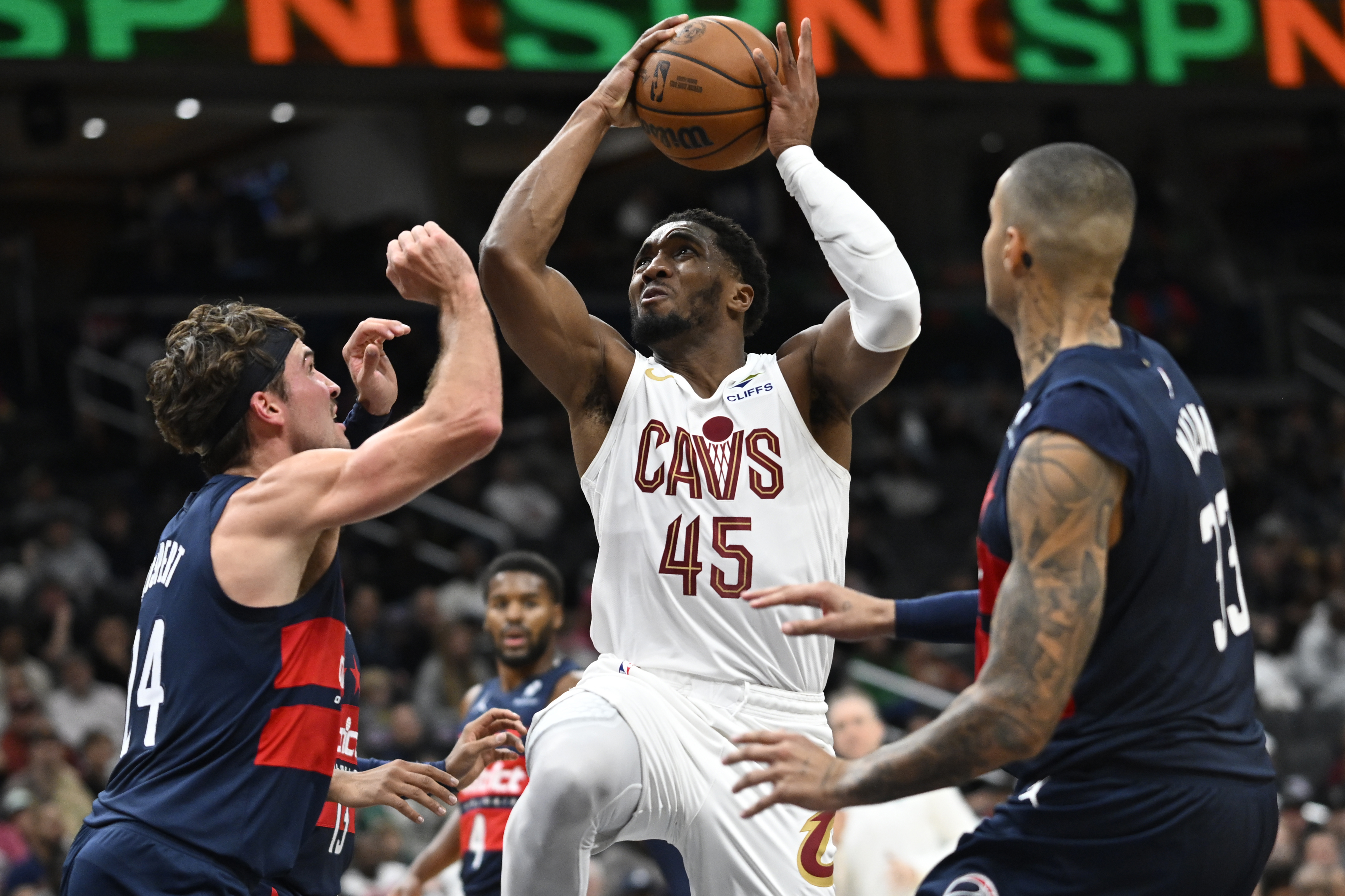 Cleveland Cavaliers guard Donovan Mitchell (45) drives between Washington Wizards forwards Corey Kispert, left, and Kyle Kuzma, right, for a basket during the first half of an NBA basketball game Saturday, Oct. 26, 2024, in Washington. 