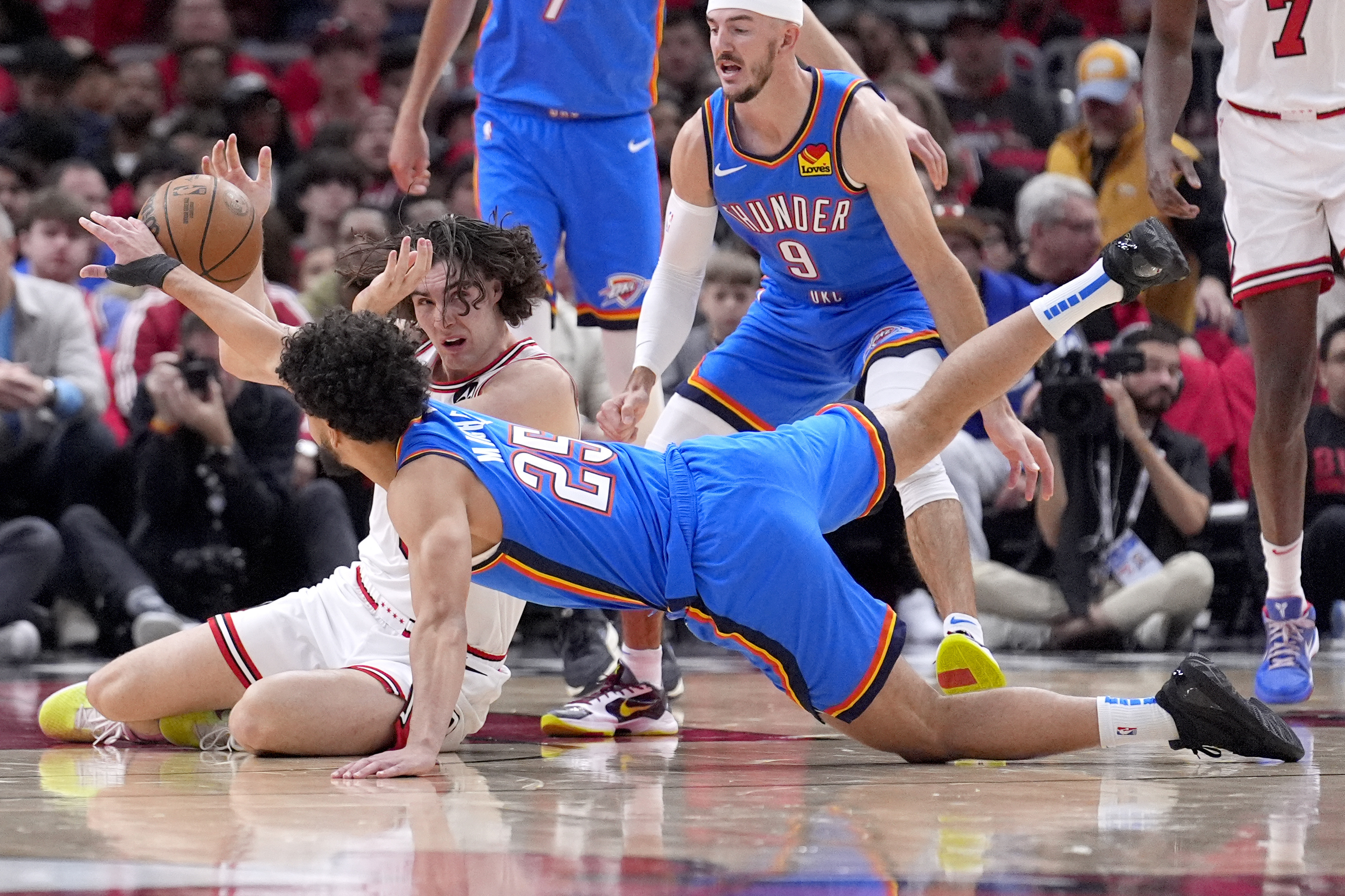 Oklahoma City Thunder's Ajay Mitchell (25) and Chicago Bulls' Josh Giddey battle for a loose ball during the first half of an NBA basketball game Saturday, Oct. 26, 2024, in Chicago. 