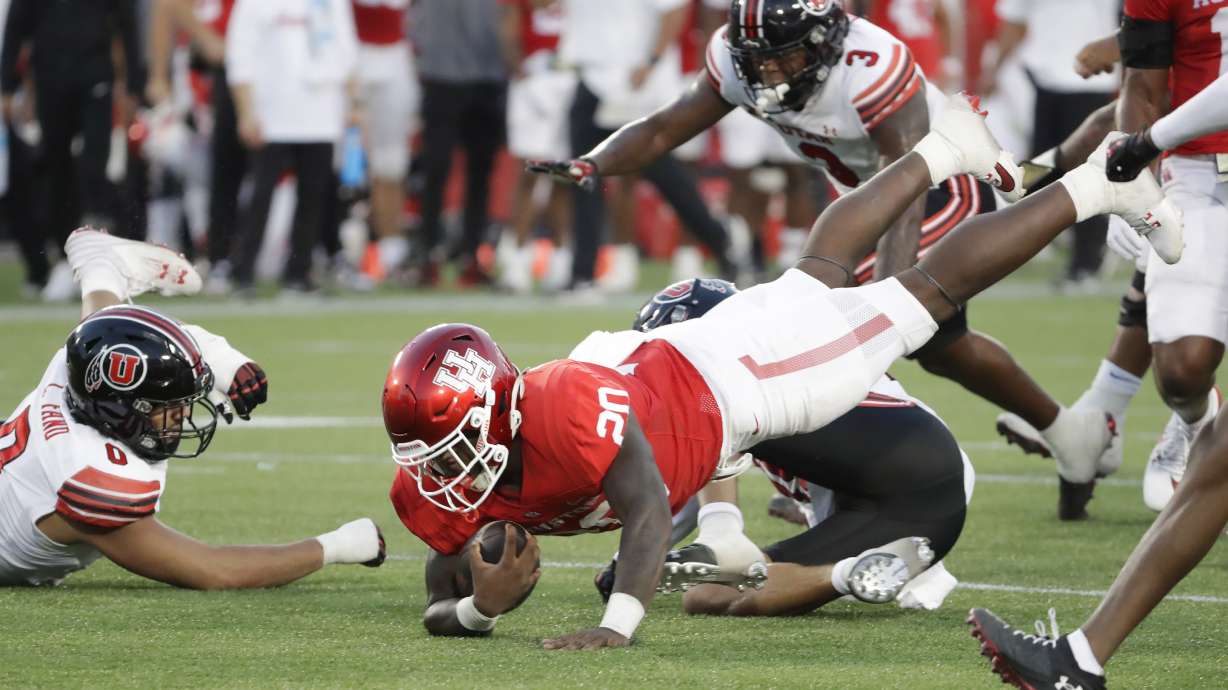 Houston running back J'Marion Burnette (20) dives for extra yardage in front of Utah defensive end Logan Fano (0) and linebacker Johnathan Hall (3) during the first half of an NCAA college football game Saturday, Oct. 26, 2024, in Houston.
