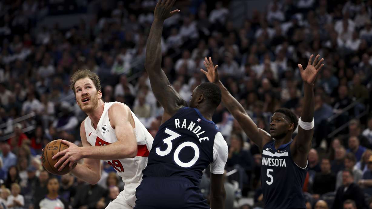 Toronto Raptors center Jakob Poeltl (19) drives toward the hoop while Minnesota Timberwolves forward Julius Randle (30) and guard Anthony Edwards (5) defend during the first half of an NBA basketball game, Saturday, Oct. 26, 2024, in Minneapolis.