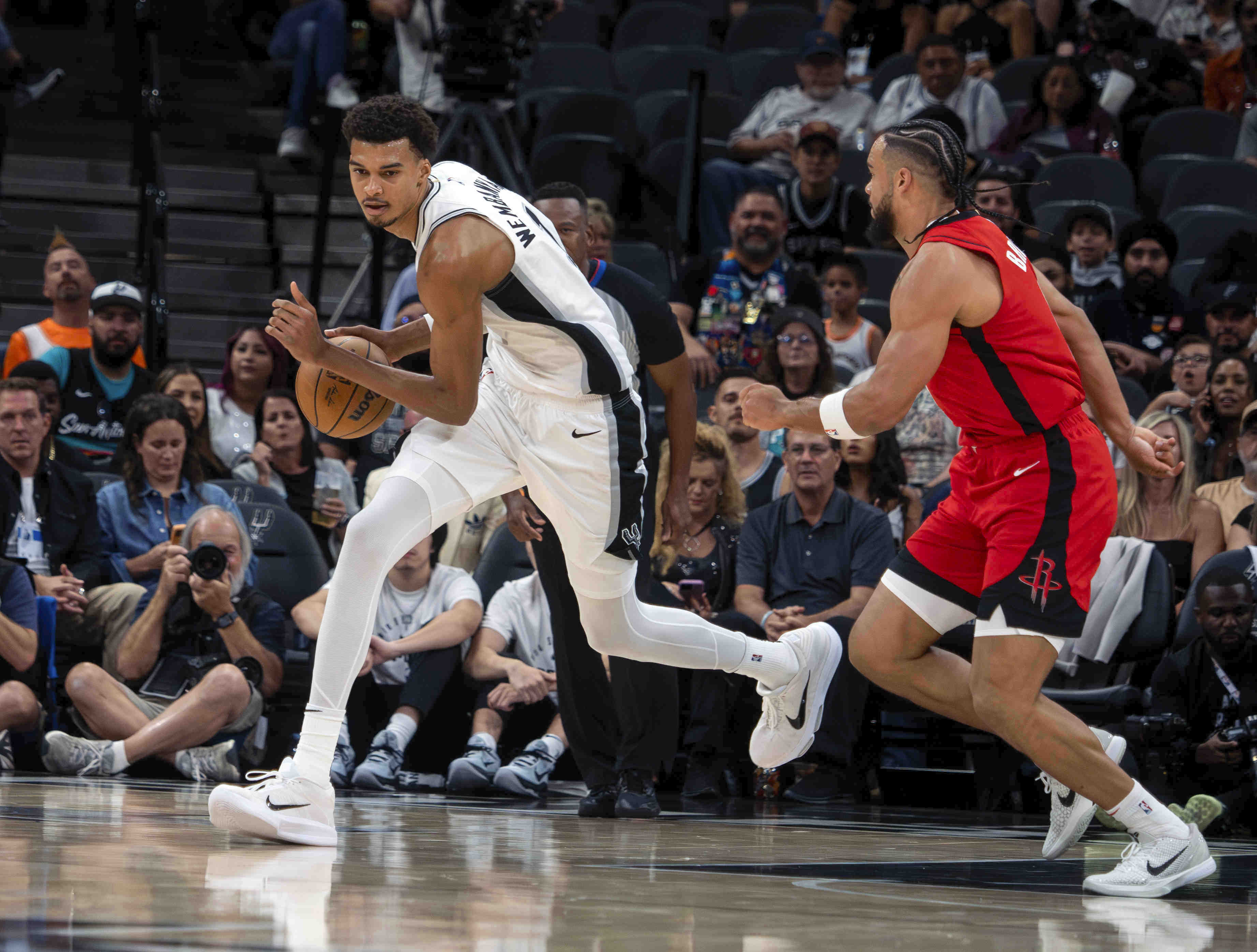 San Antonio Spurs forward Victor Wembanyama, left, dribbles against Houston Rockets guard Dillon Brooks, right, during the first half an NBA basketball game, Saturday, Oct. 26, 2024, in San Antonio. 