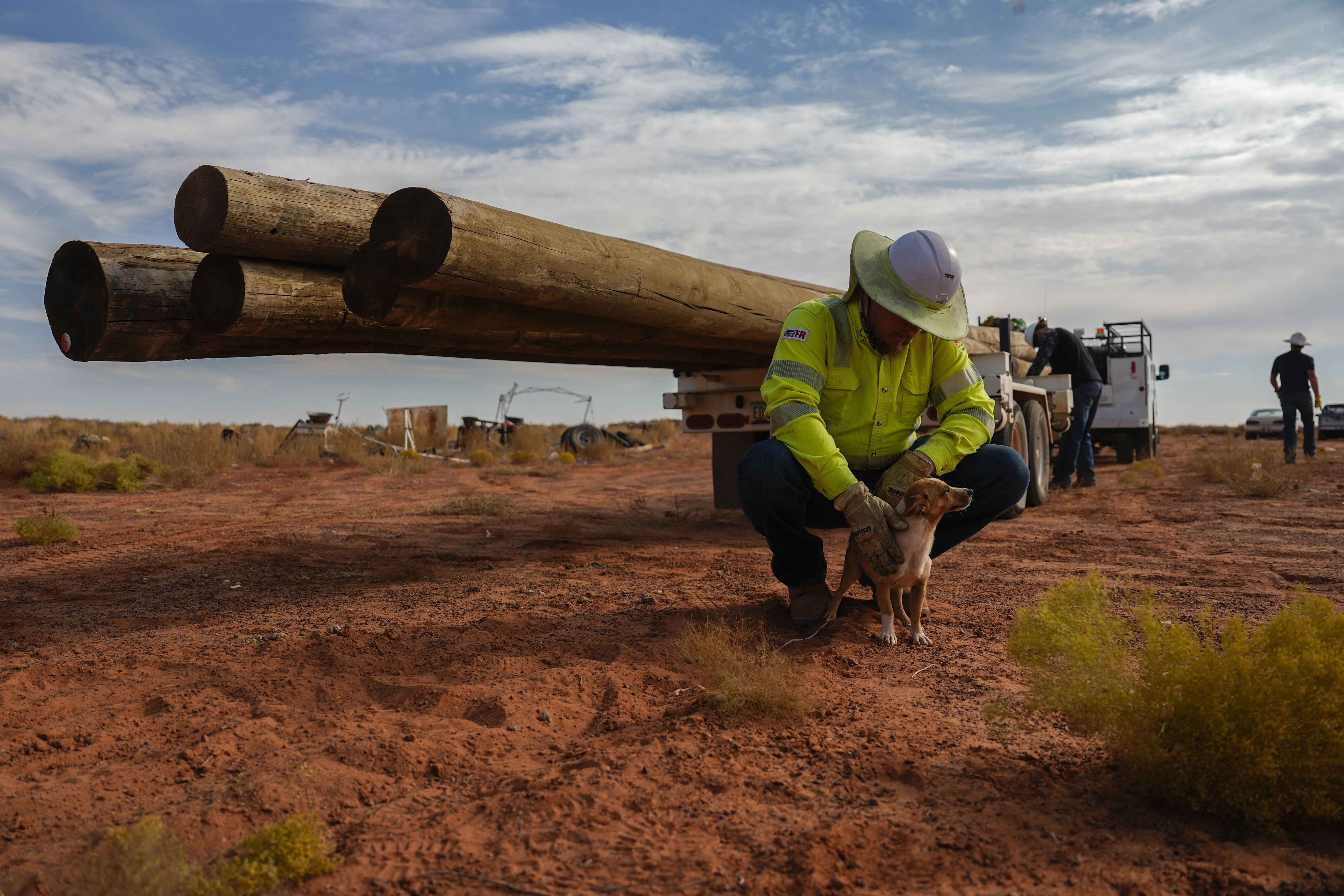 A volunteer pets a dog before starting power line construction for a home, Oct. 8, on the Navajo Nation in Halchita, Utah.