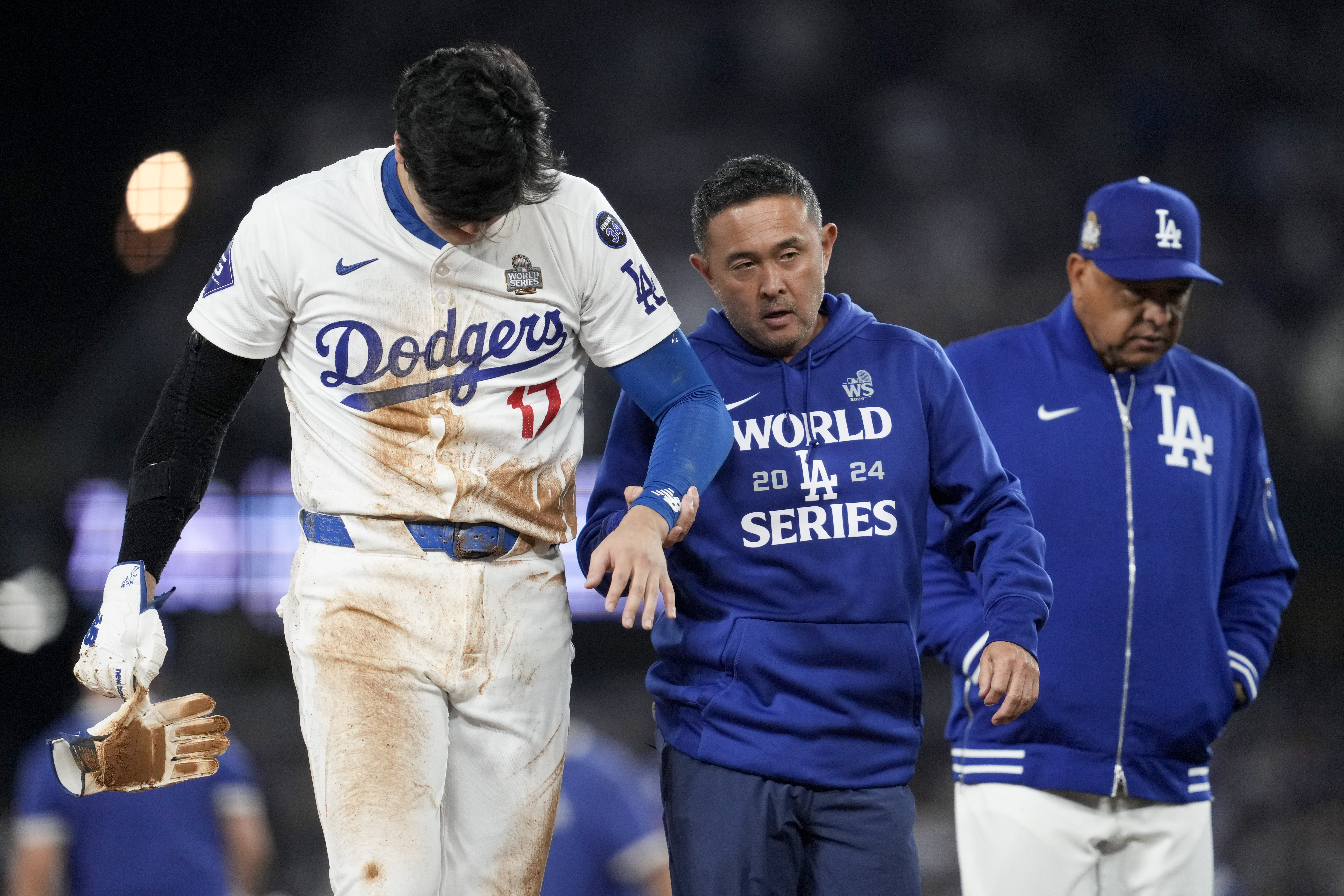 Los Angeles Dodgers' Shohei Ohtani is helped off the field after getting hurt during the seventh inning in Game 2 of the baseball World Series against the New York Yankees, Saturday, Oct. 26, 2024, in Los Angeles.
