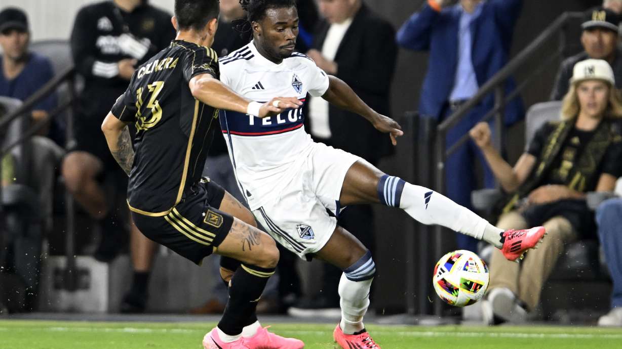 Vancouver Whitecaps defender Sam Adekugbe, right, controls the ball against Los Angeles FC forward Cristian Olivera (13) during the first half of the first match of an MLS Cup playoffs opening round in Los Angeles, Sunday, Oct. 27, 2024.