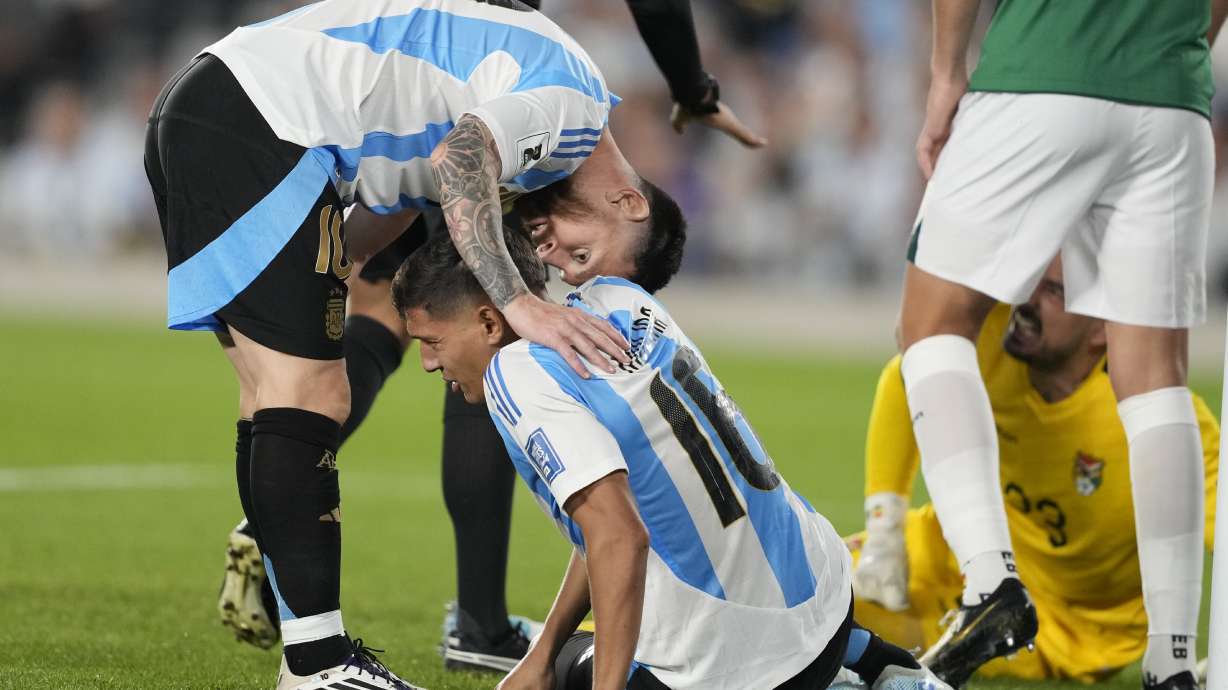 Argentina's Lionel Messi checks on teammate Nahuel Molina who sits on the pitch with an injury during a World Cup 2026 qualifying soccer match against Bolivia at Monumental stadium in Buenos Aires, Argentina, Tuesday, Oct. 15, 2024.