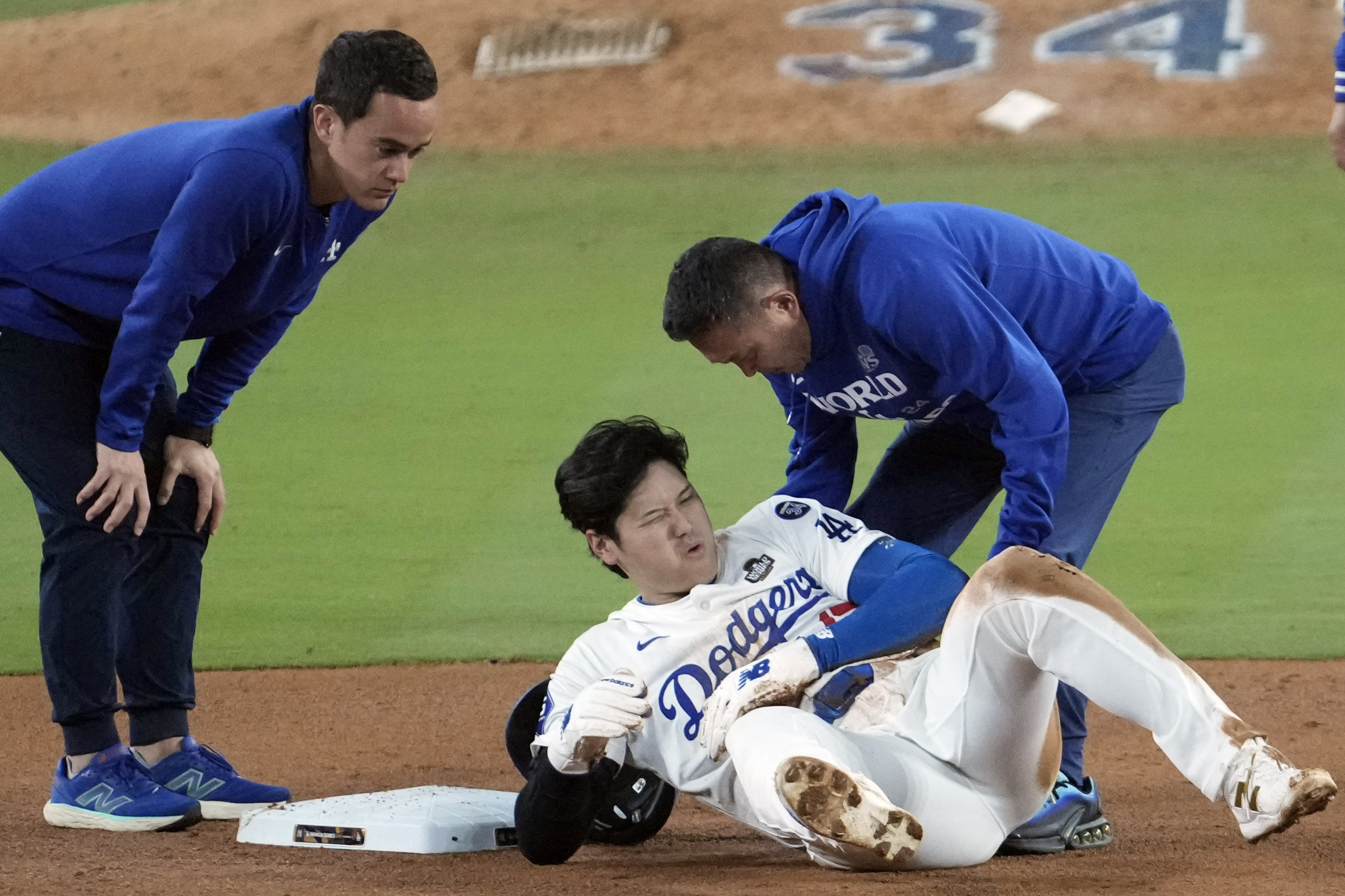 Los Angeles Dodgers' Shohei Ohtani, center, reacts after being injured while trying to steal second base against the New York Yankees during the seventh inning in Game 2 of the baseball World Series, Saturday, Oct. 26, 2024, in Los Angeles. 