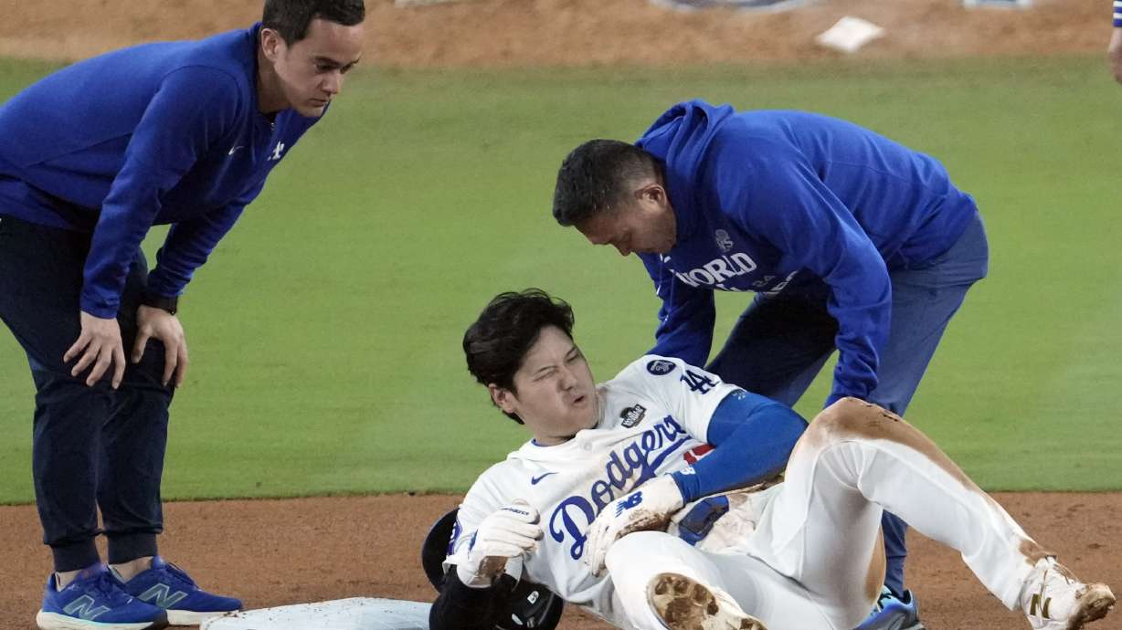 Los Angeles Dodgers' Shohei Ohtani, center, reacts after being injured while trying to steal second base against the New York Yankees during the seventh inning in Game 2 of the baseball World Series, Saturday, Oct. 26, 2024, in Los Angeles.