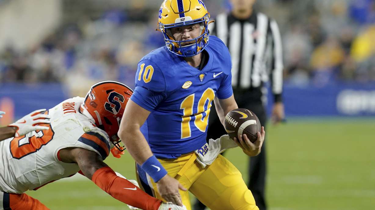 Pittsburgh quarterback Eli Holstein (10) carries as he's defended by Syracuse defensive back Devin Grant (23) during the first half of an NCAA college football game, Thursday, Oct. 24, 2024, in Pittsburgh.